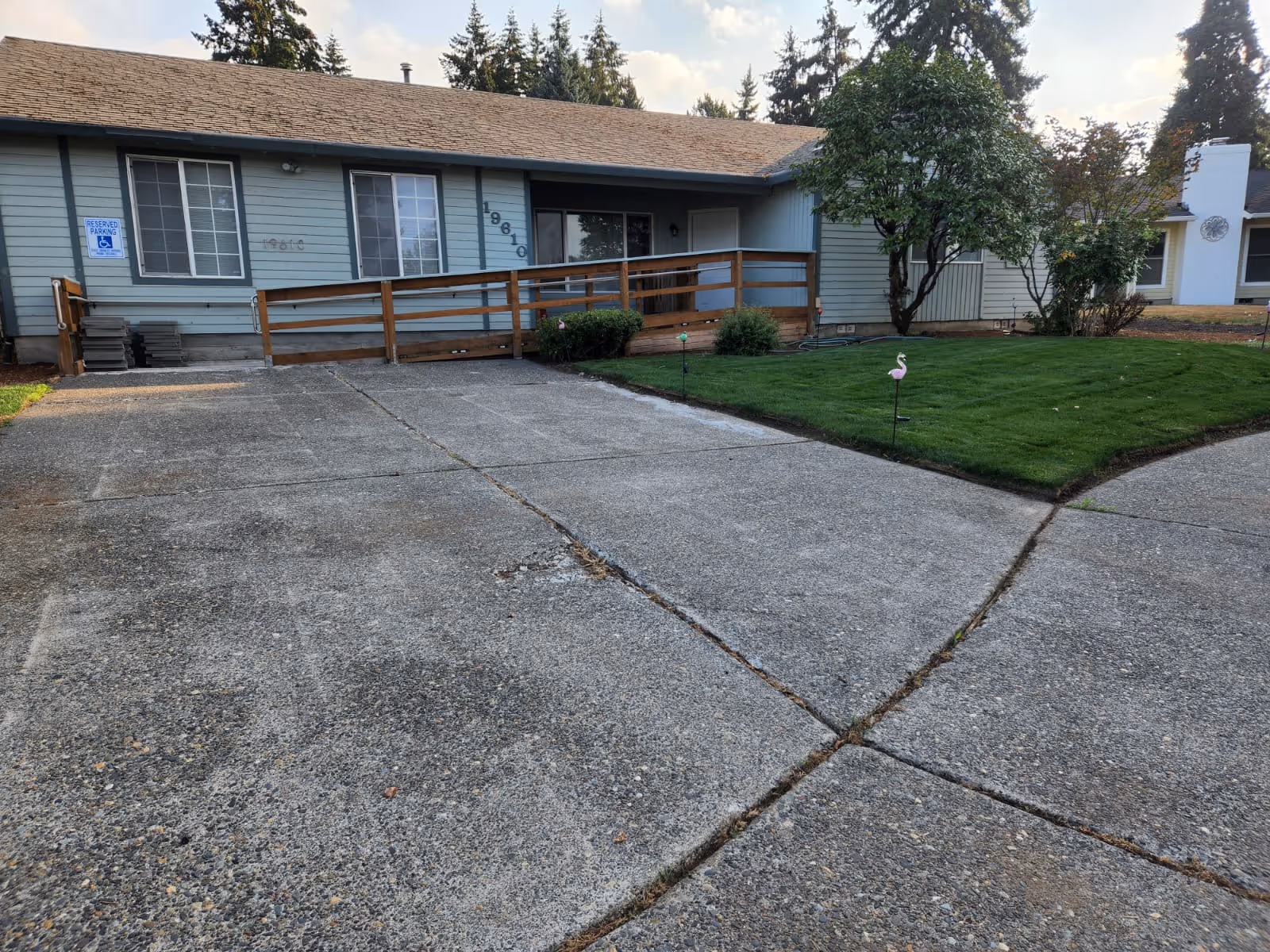 Single-story blue senior living facility with a ramp, parking area, and green lawn.