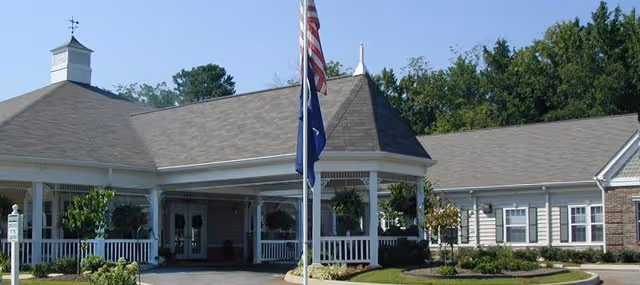 Front exterior view of Oaks at Greenwood with entrance, porch, and flagpole.