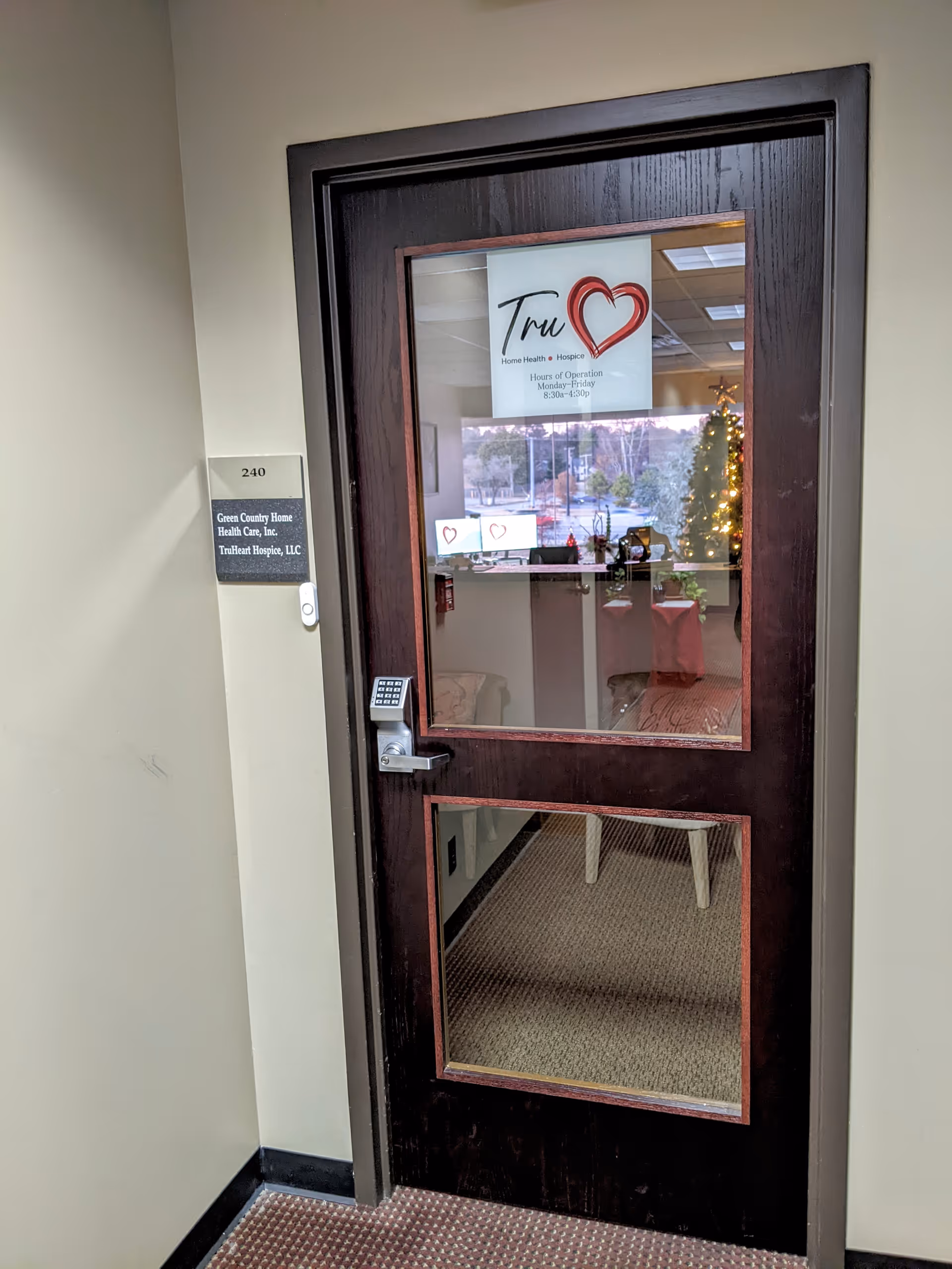 Dark wooden door with glass panels and a keypad in a beige hallway.