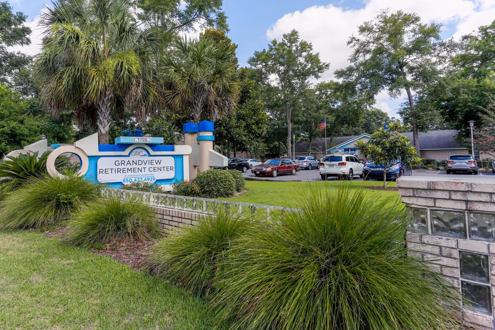 Entrance sign and landscaped front lawn of Grandview Retirement Center with parked cars and the building in the background.