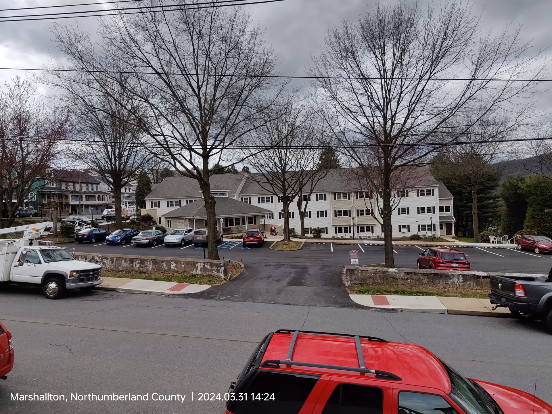 Exterior view of Sheridan Court senior living building with parking lot and leafless trees.
