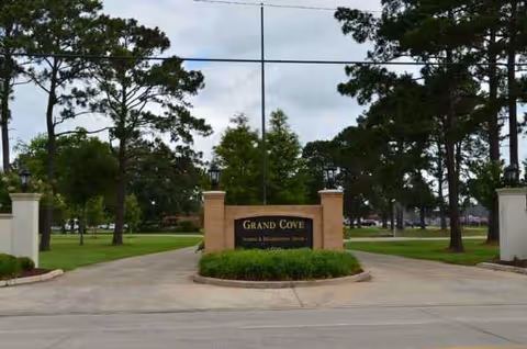 Grand Cove entrance sign with brick pillars and manicured landscaping along the driveway.