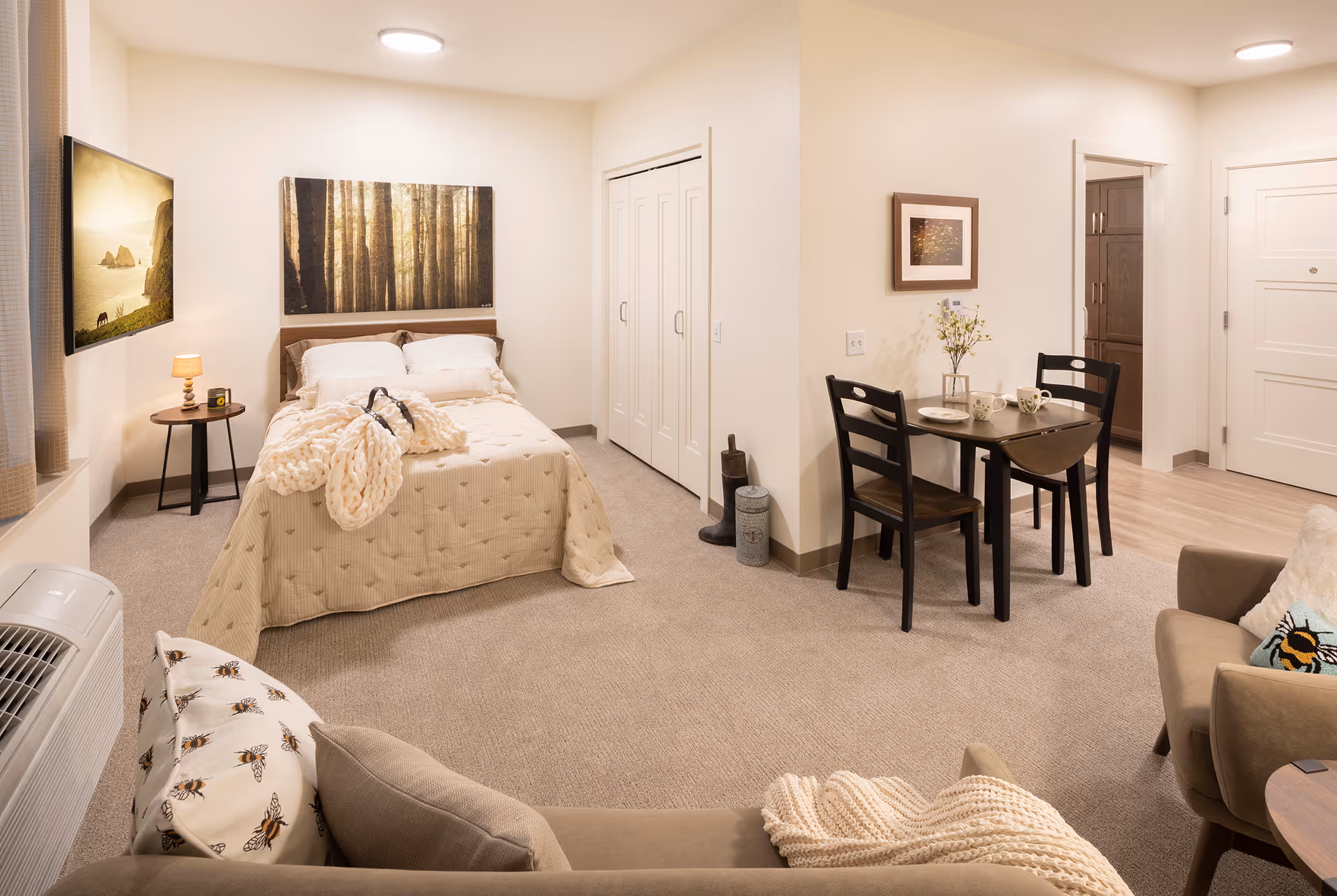 Cozy furnished studio apartment with bed, dining area, and sofa in TLC Living Community.