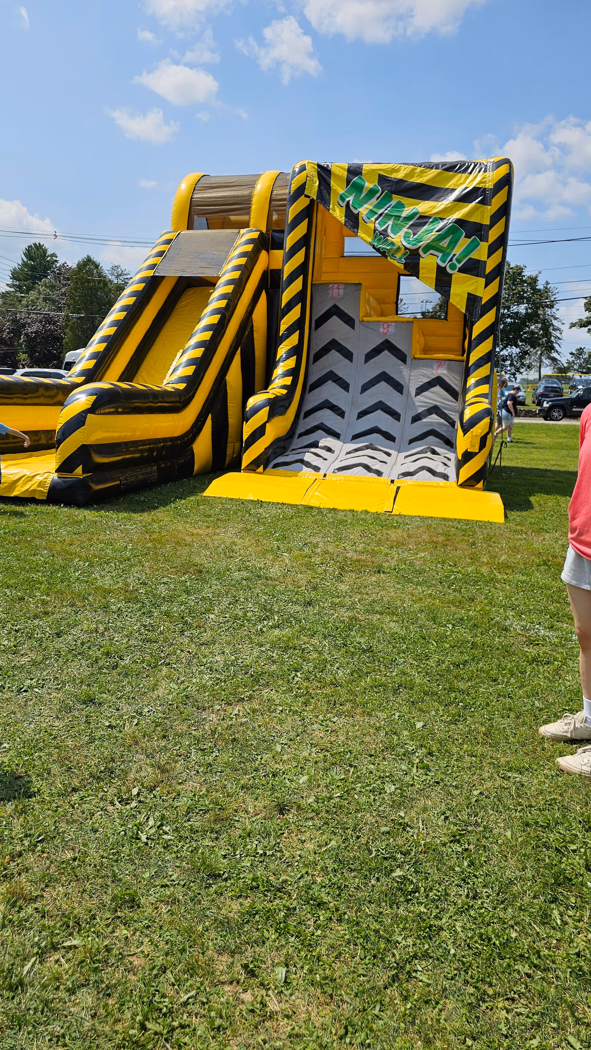 Large yellow and black inflatable obstacle course on a grassy outdoor field.