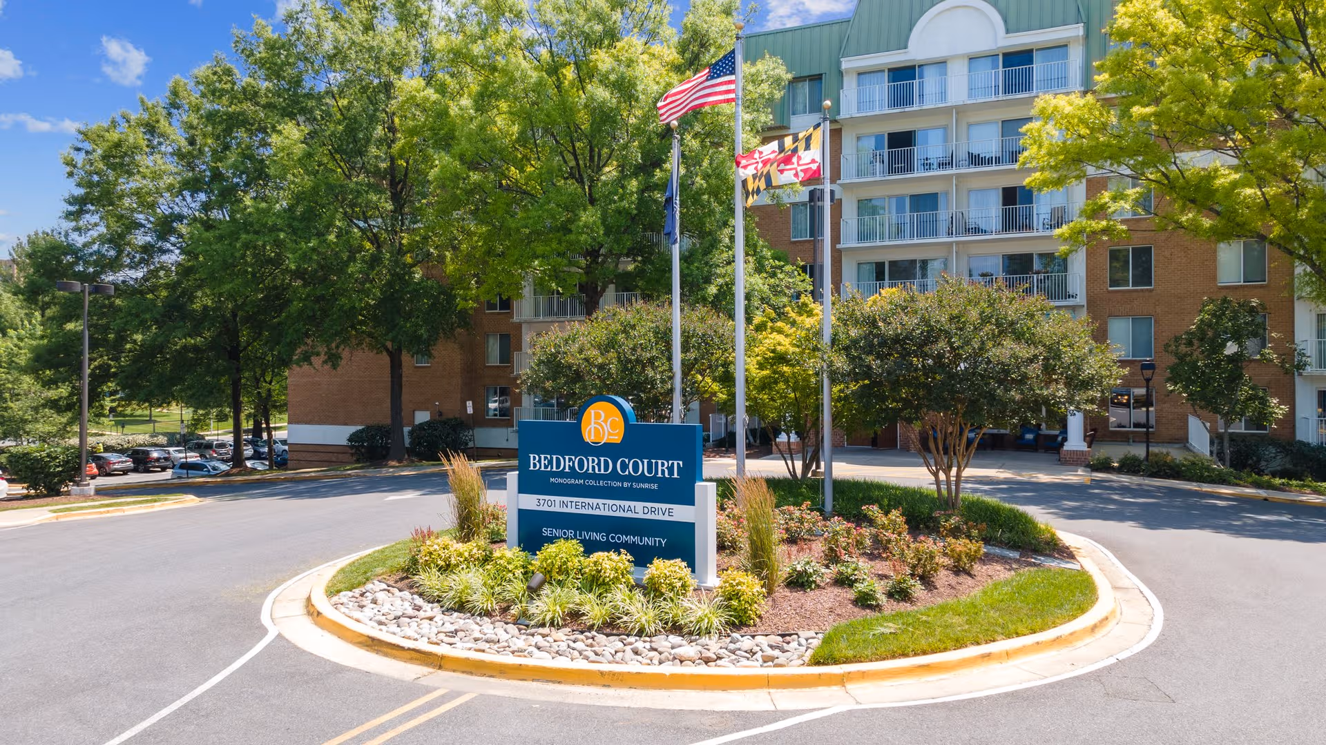 Exterior view of Bedford Court senior living building with circular driveway and sign.