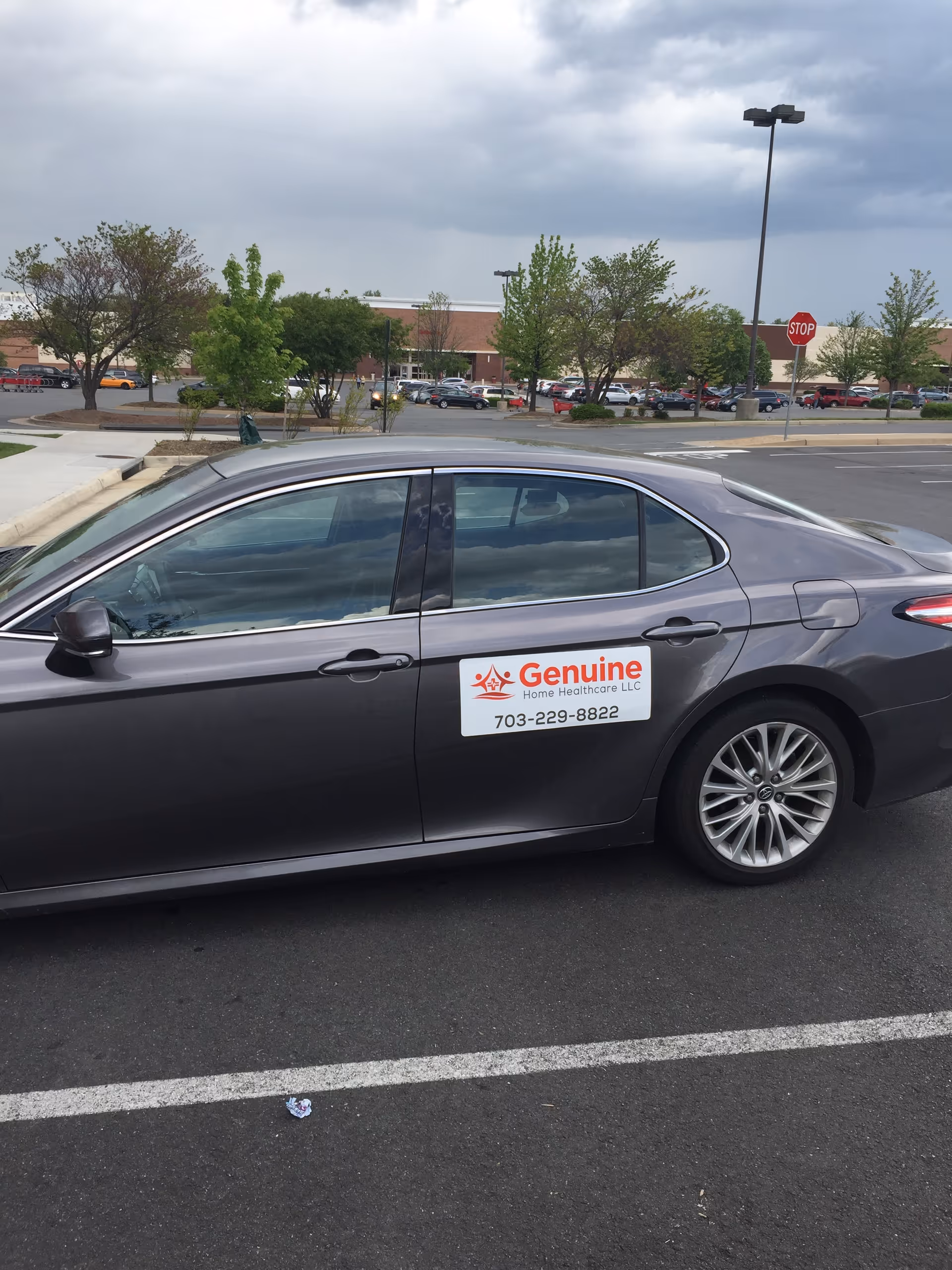 Gray sedan in parking lot displays Genuine Home Healthcare LLC sign on door.