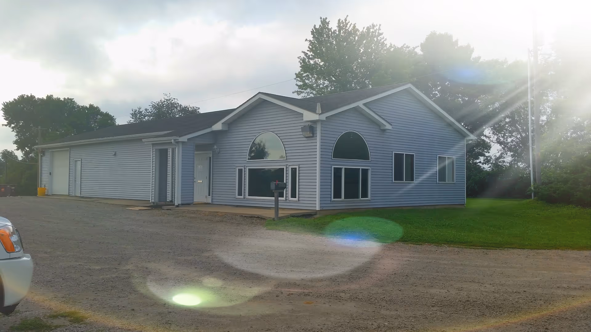 Blue single-story facility exterior with arched windows, parking, and green lawn.