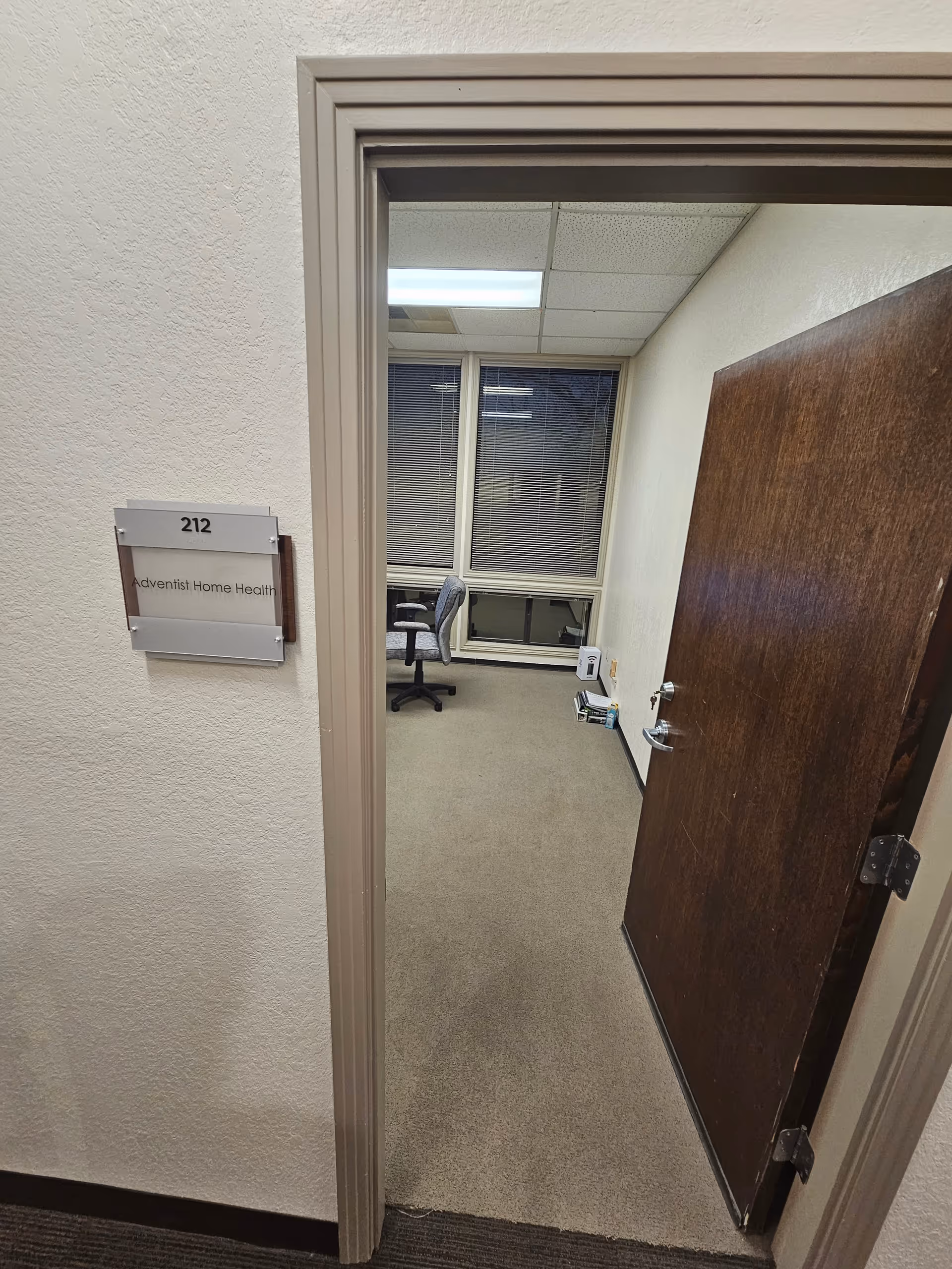 Doorway into a small office with chair, desk, window, and Adventist Home Health sign.