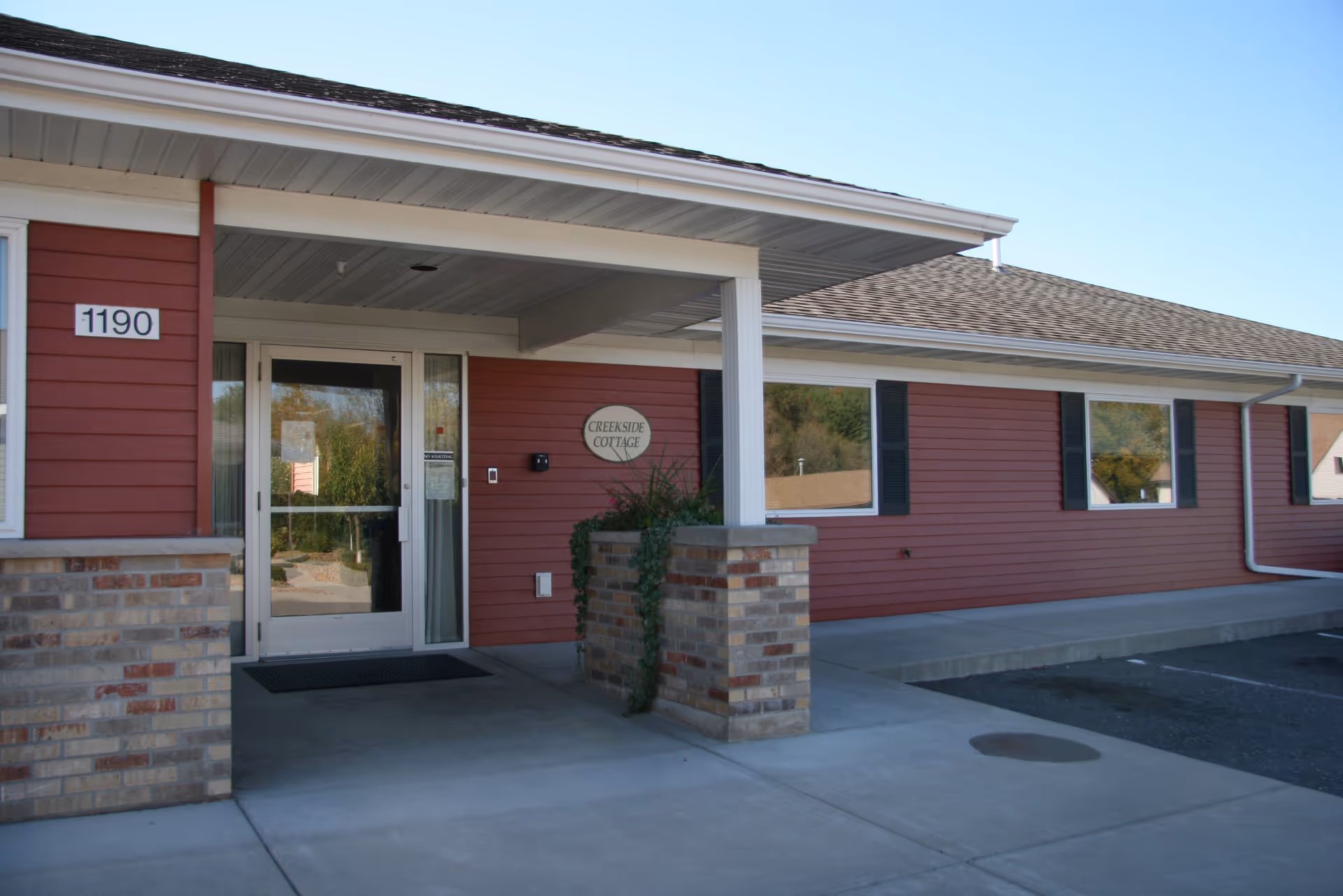 Red siding building exterior with a covered entrance and Creekside Cottage sign