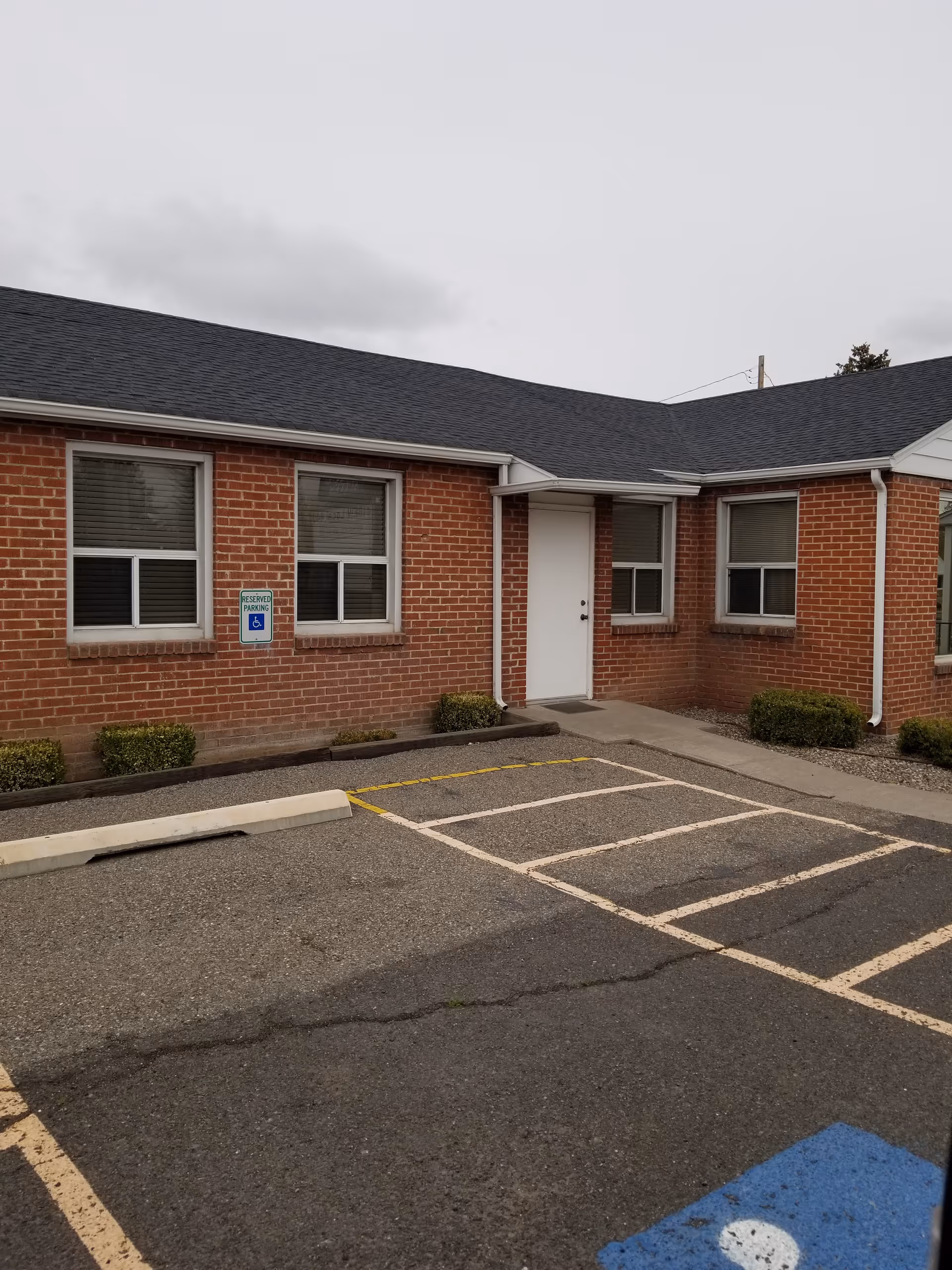 Brick senior care facility exterior with a parking lot and accessible entrance.