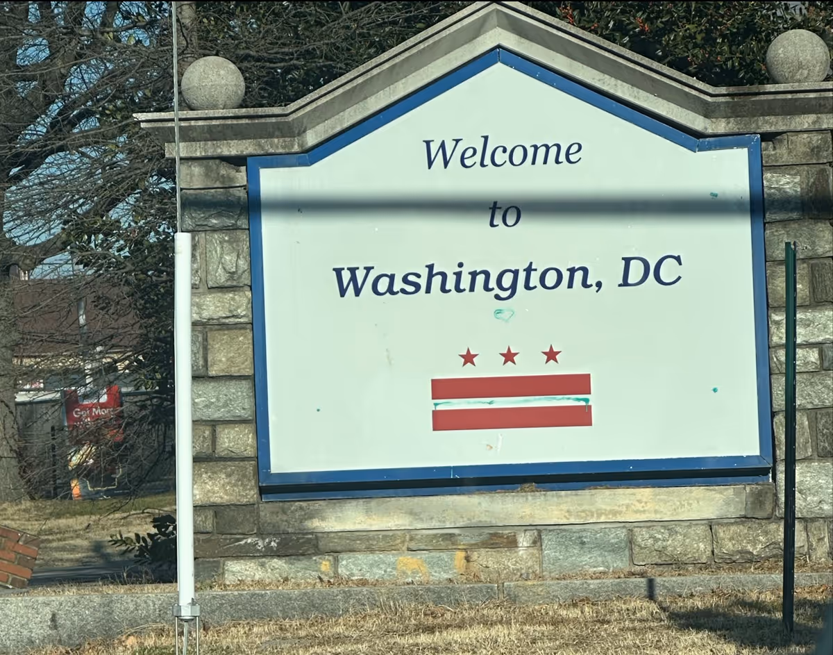 Stone-framed welcome sign reading 'Welcome to Washington, DC' outdoors.