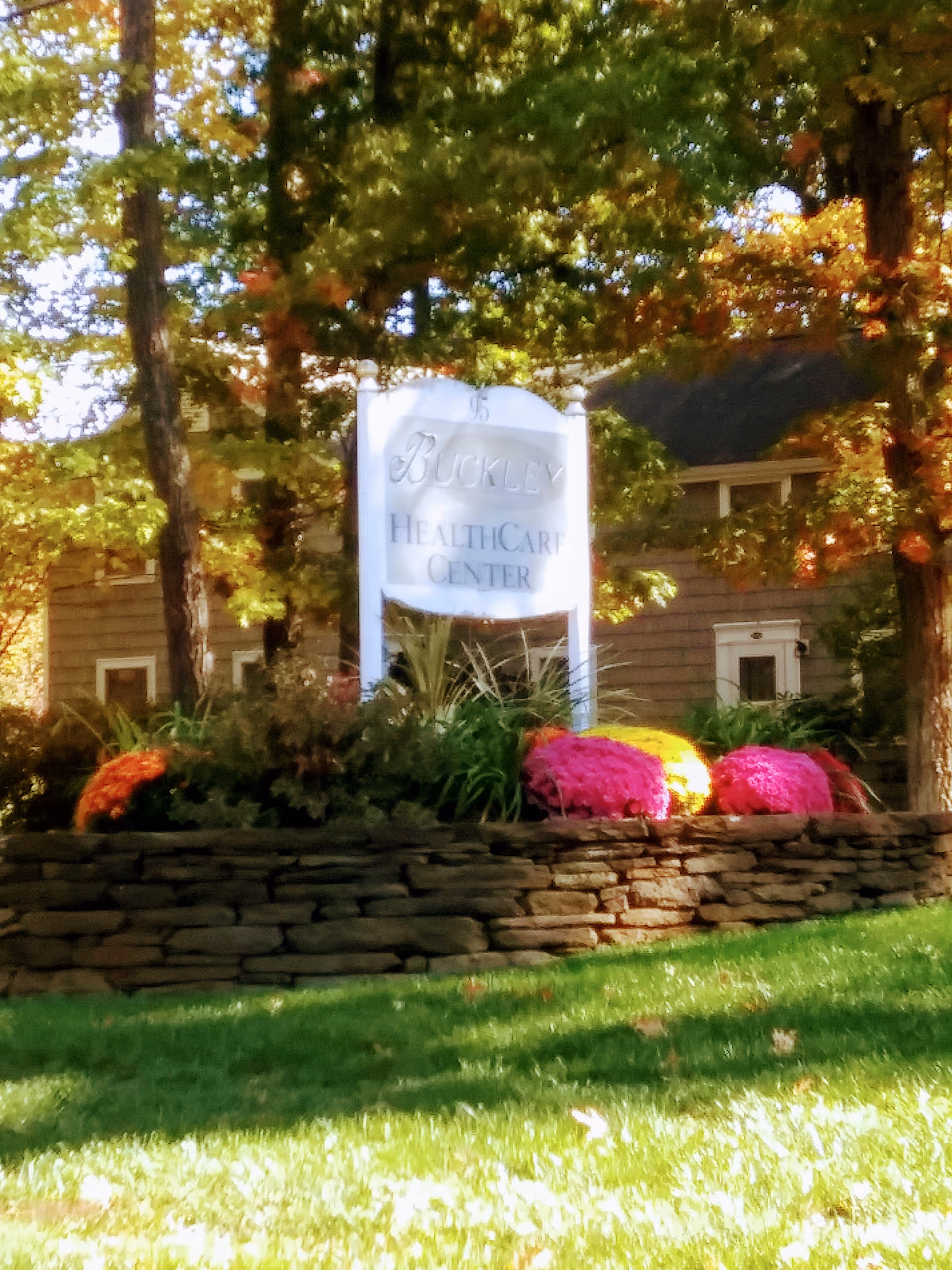 Buckley Healthcare Center sign amid a stone planter and colorful flowers