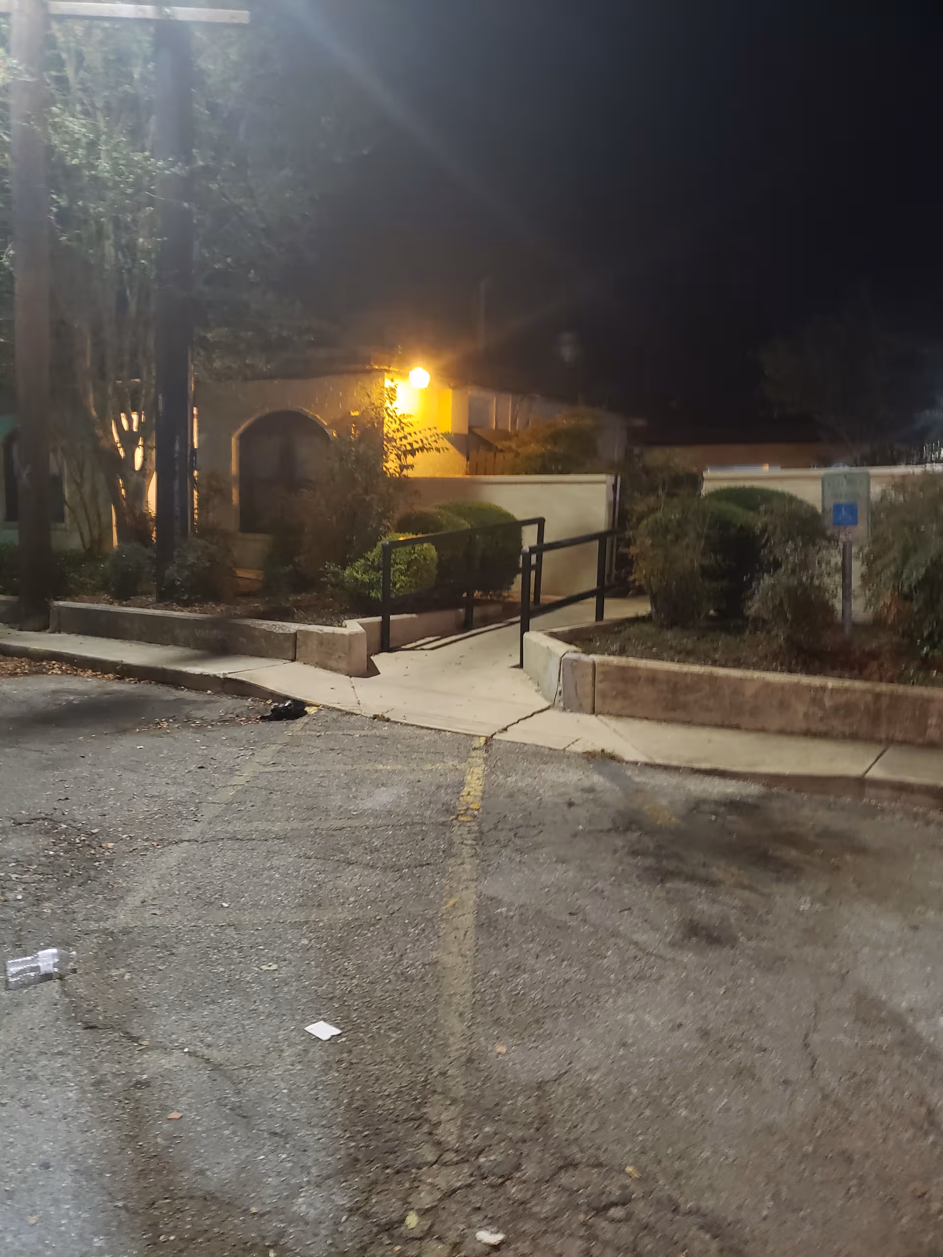 Night exterior of San Jose Nursing Center with a walkway, ramp, and landscaping near the entrance.