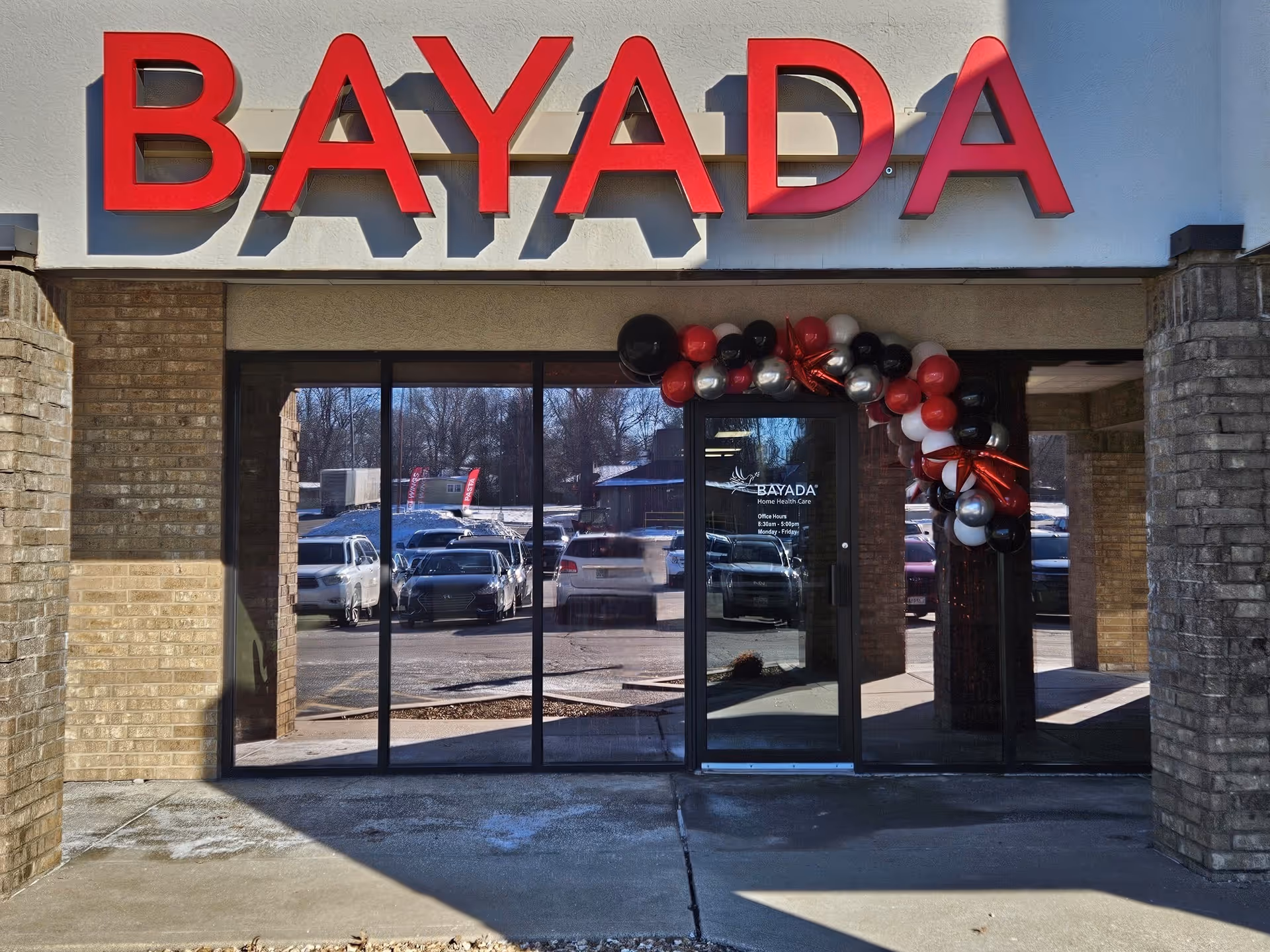 Exterior view of BAYADA Habilitation Springfield with glass doors and red balloon arch.