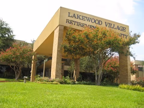 Exterior view of Lakewood Village Retirement Community entrance with trees and lawn.