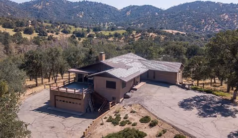 A single-story treatment center sits on a hillside with a curved driveway and surrounding trees.