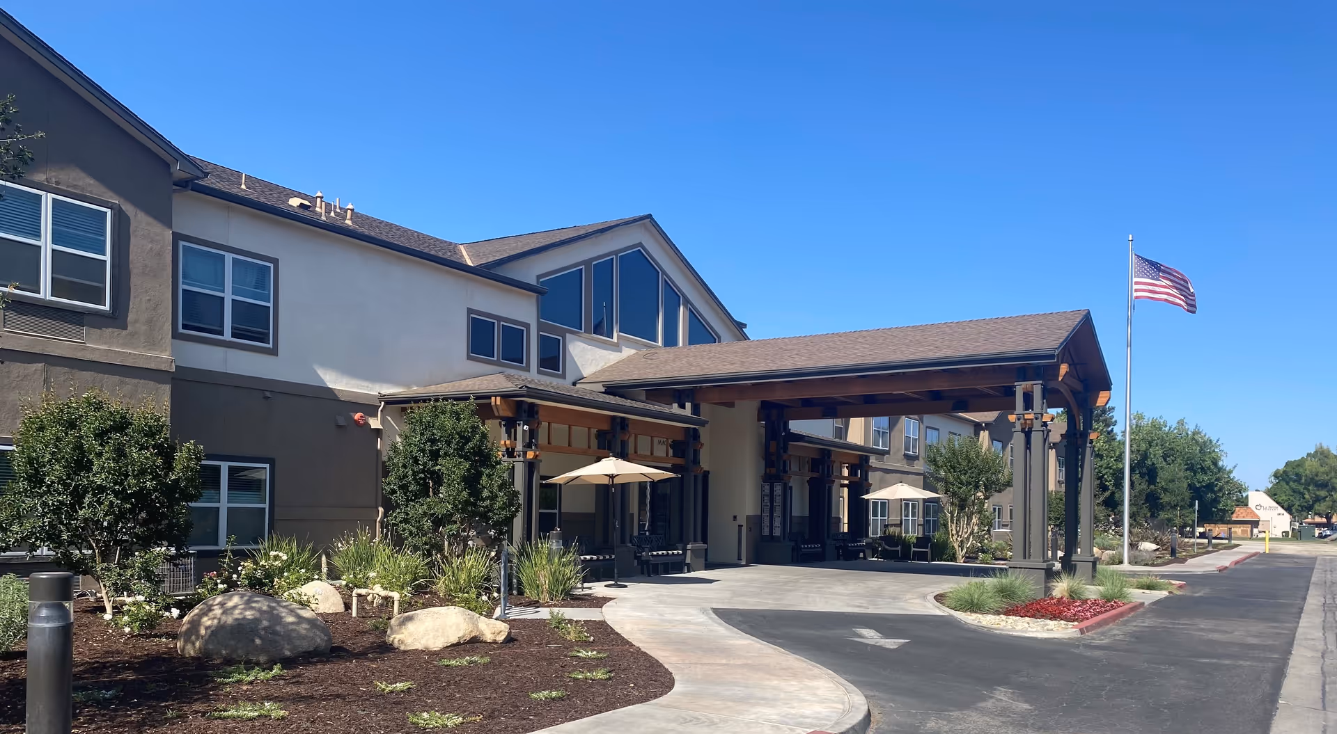 Exterior view of Magnolia Place senior living facility with a covered entrance and flag.