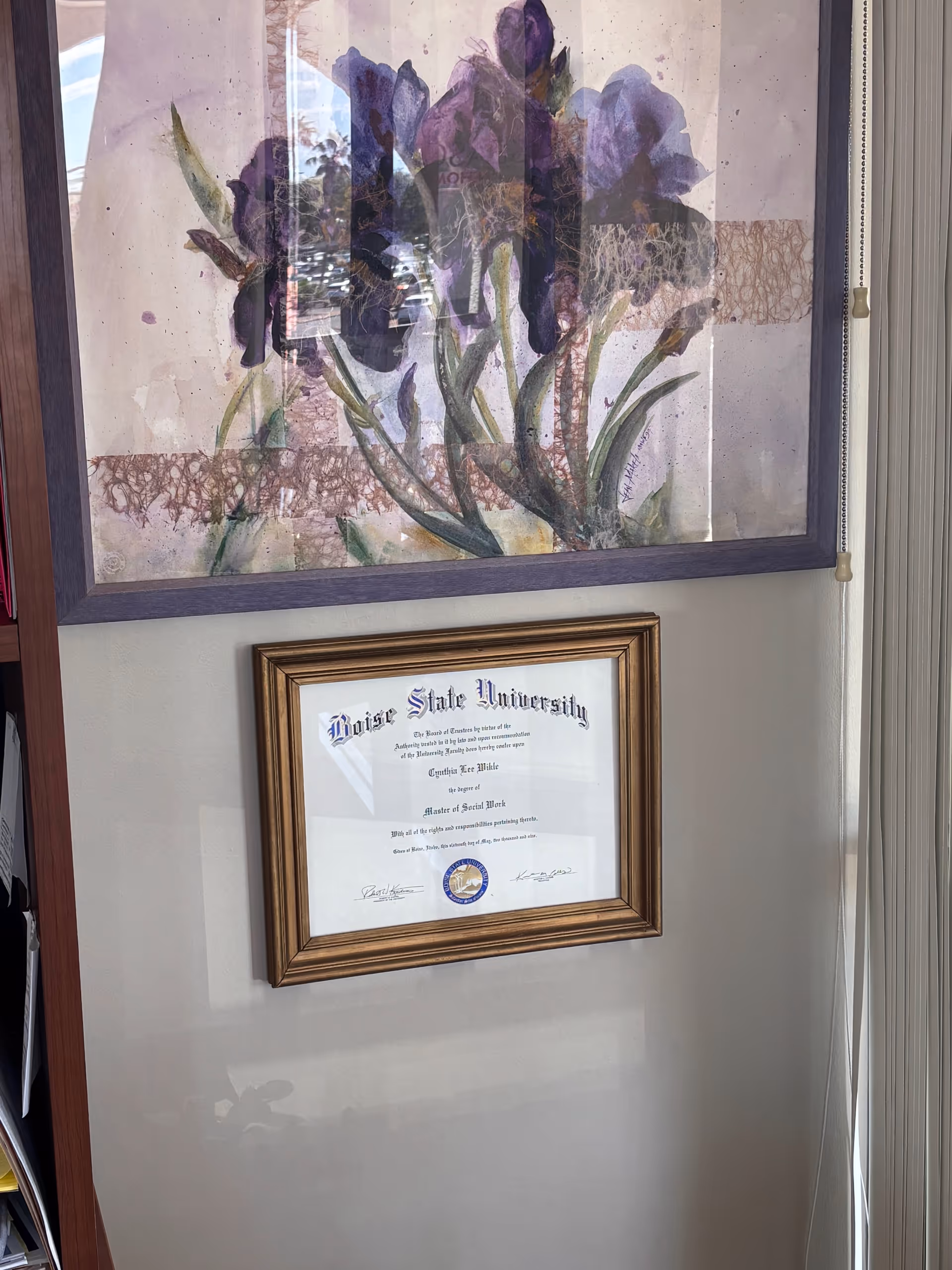 Interior wall with a large flower painting and a framed diploma underneath