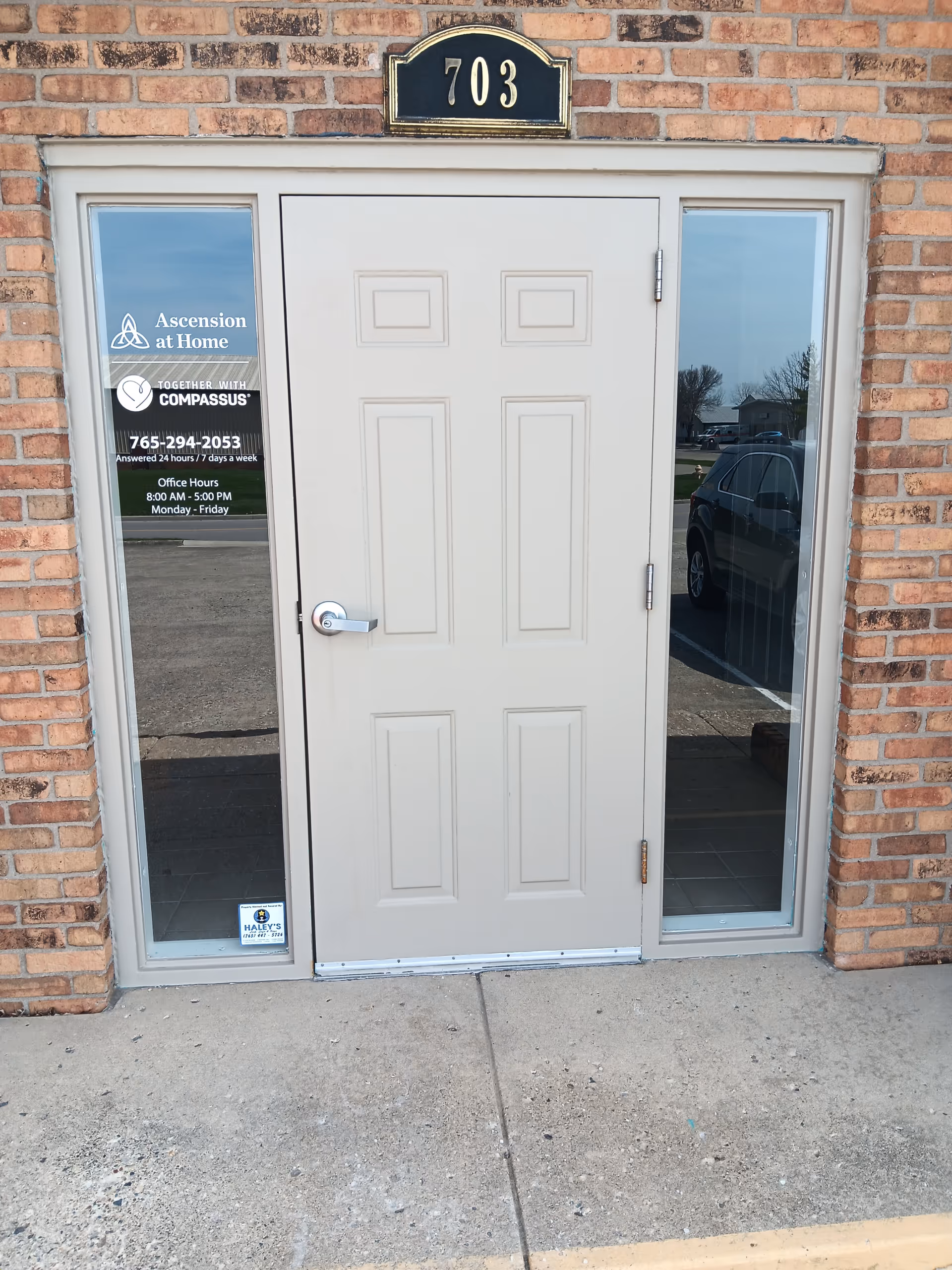 Front entrance to Ascension at Home facility, brick exterior, glass side panels, and numbered plaque 703.