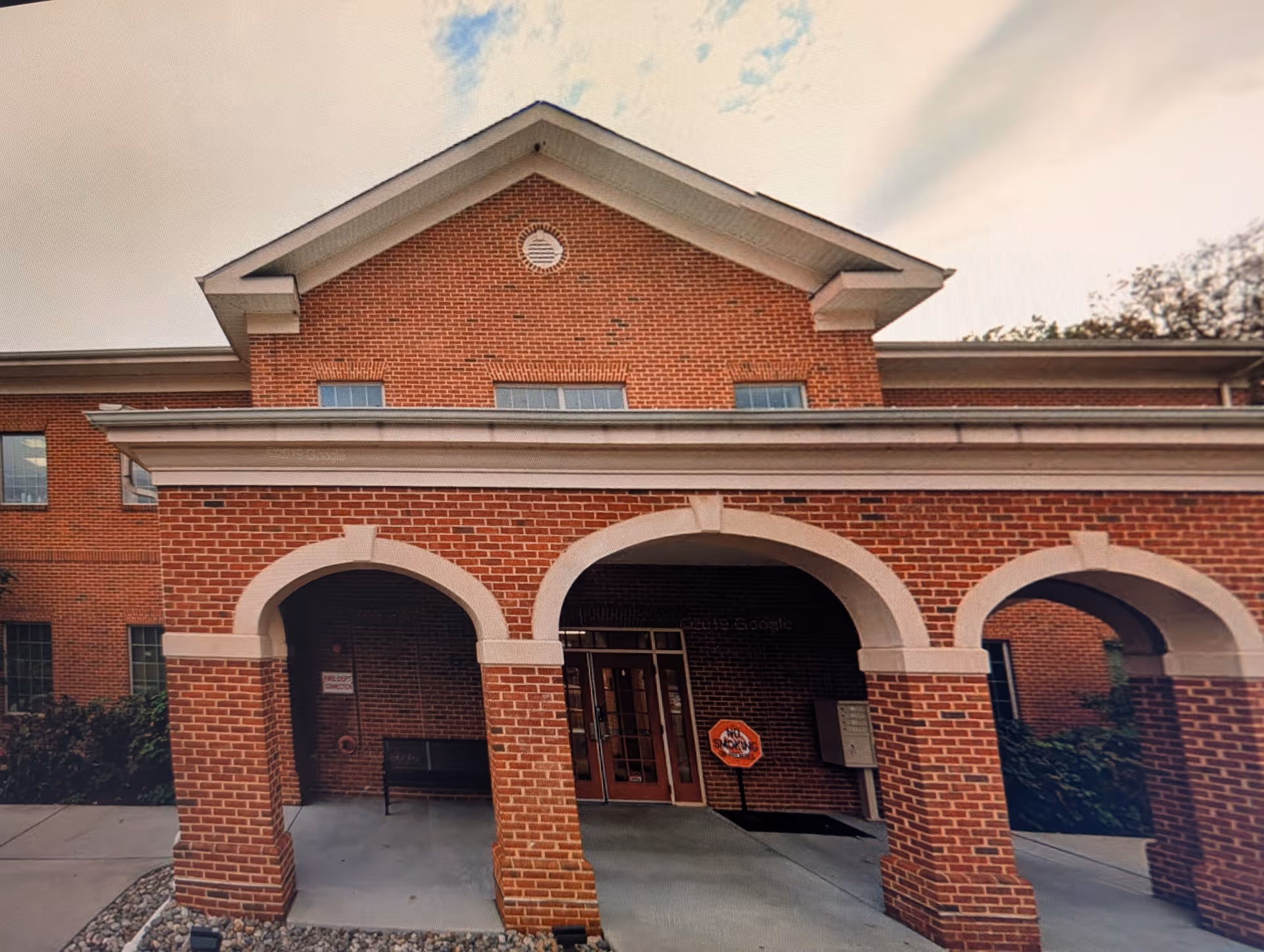 Brick senior living facility exterior featuring three arched entryways and a gabled roof.