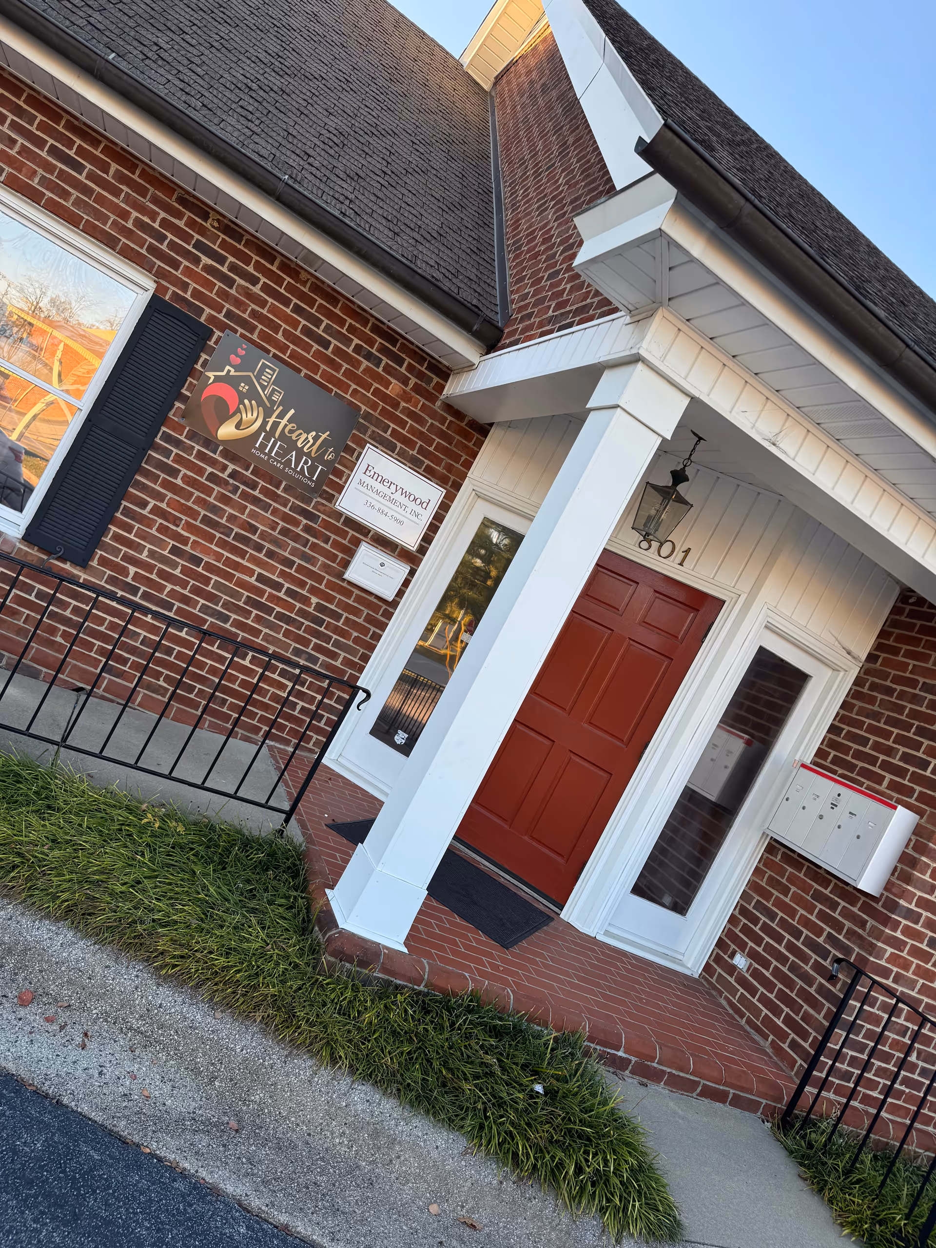 Brick exterior entrance with red door, white columns, and Heart to Heart Home Care Solutions sign.