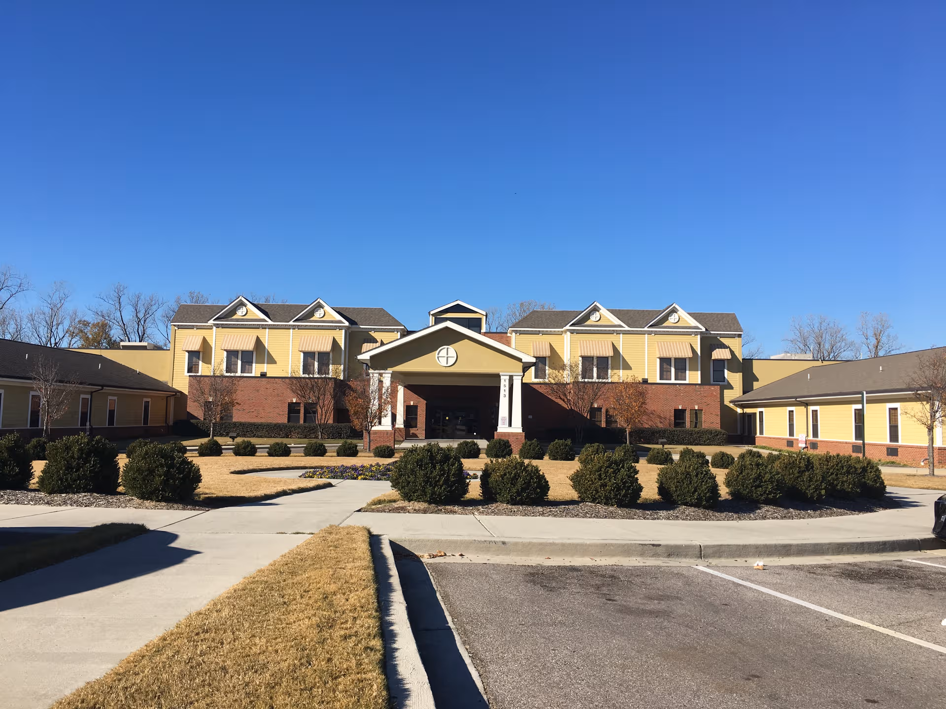 AHC Harbor View senior living facility exterior with yellow siding and manicured landscaping.
