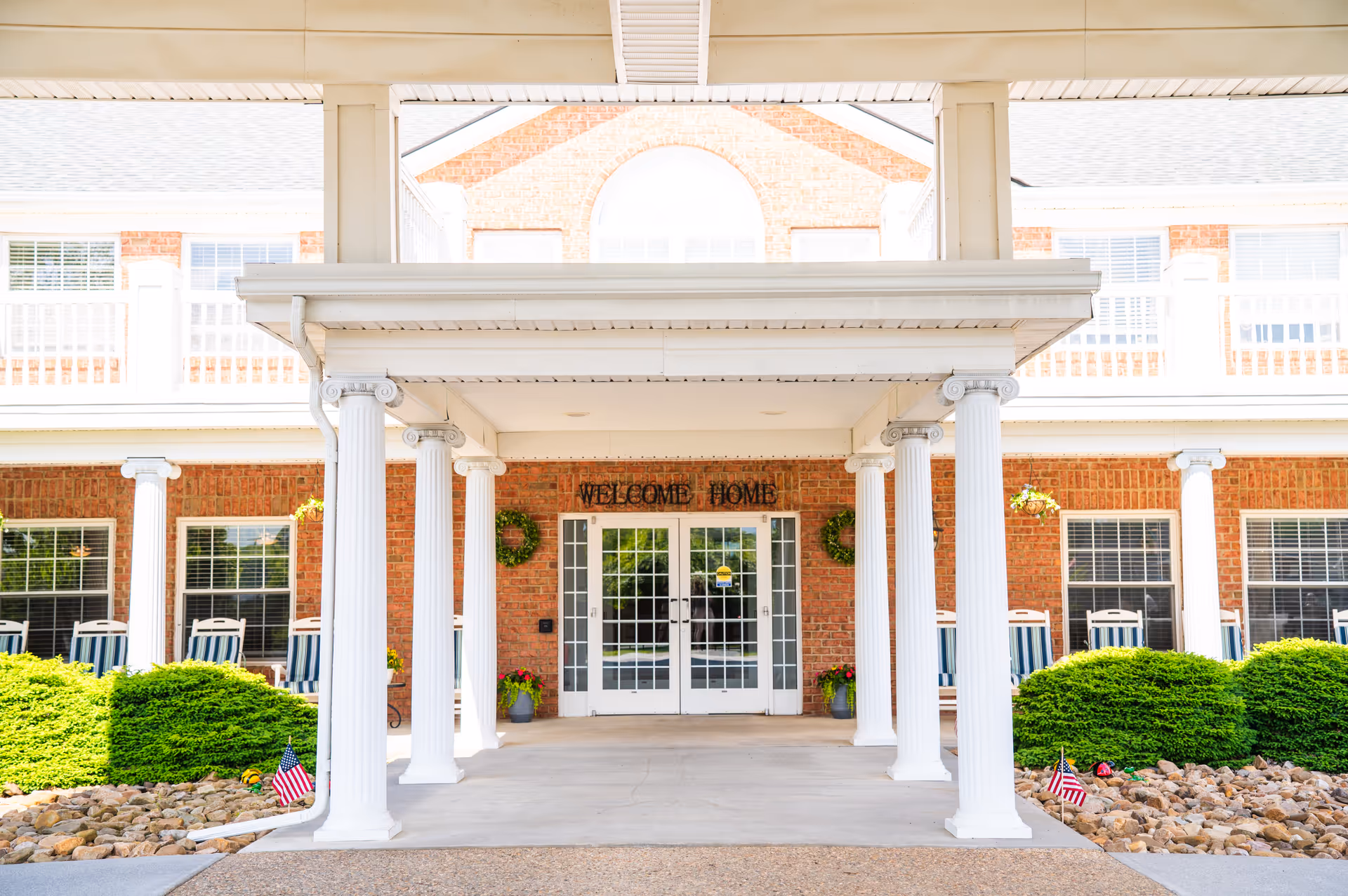 Exterior view of Commonwealth Senior Living at Christiansburg entrance with columns and a welcome sign