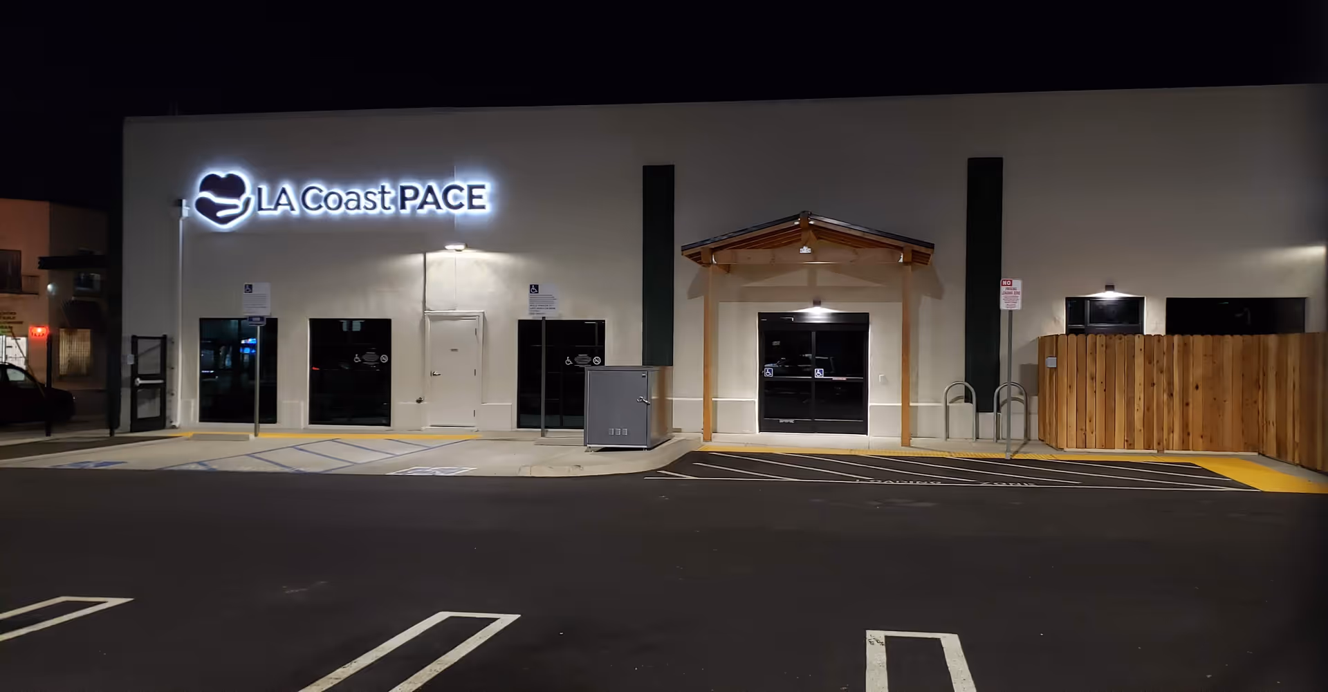 Night exterior of a building with LA Coast PACE sign and parking lot.