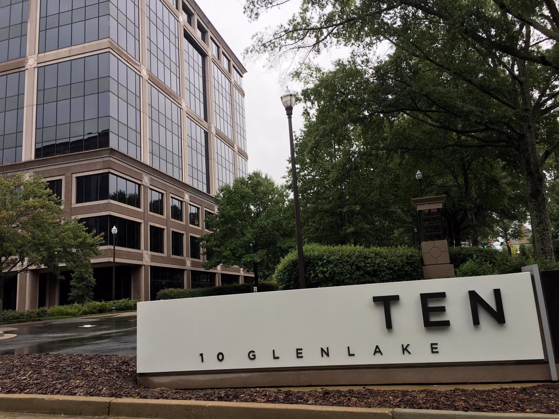 Modern glass-fronted building with a prominent TEN sign and surrounding trees.