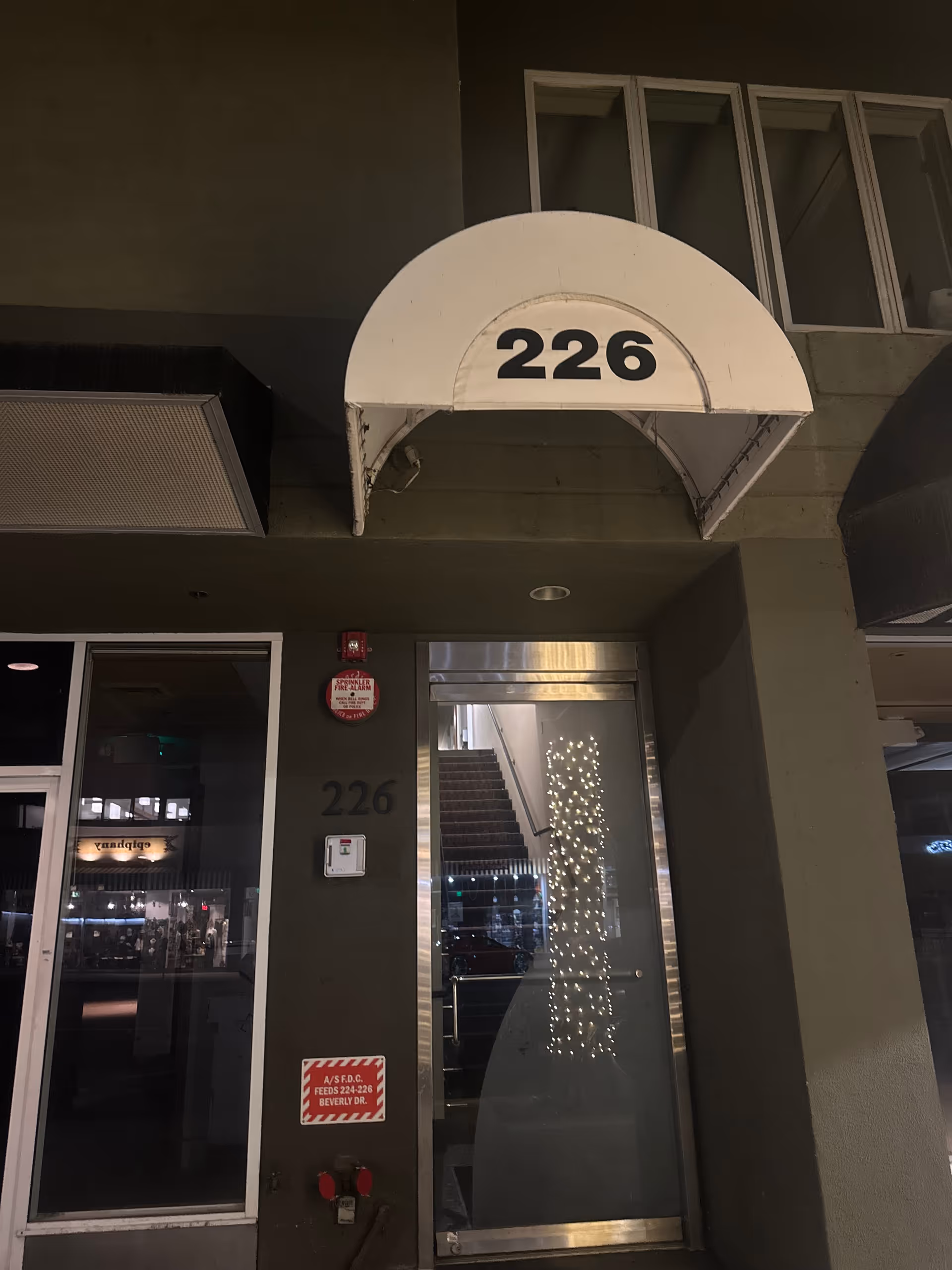 Exterior building entrance with a rounded white canopy labeled '226' and glass door.