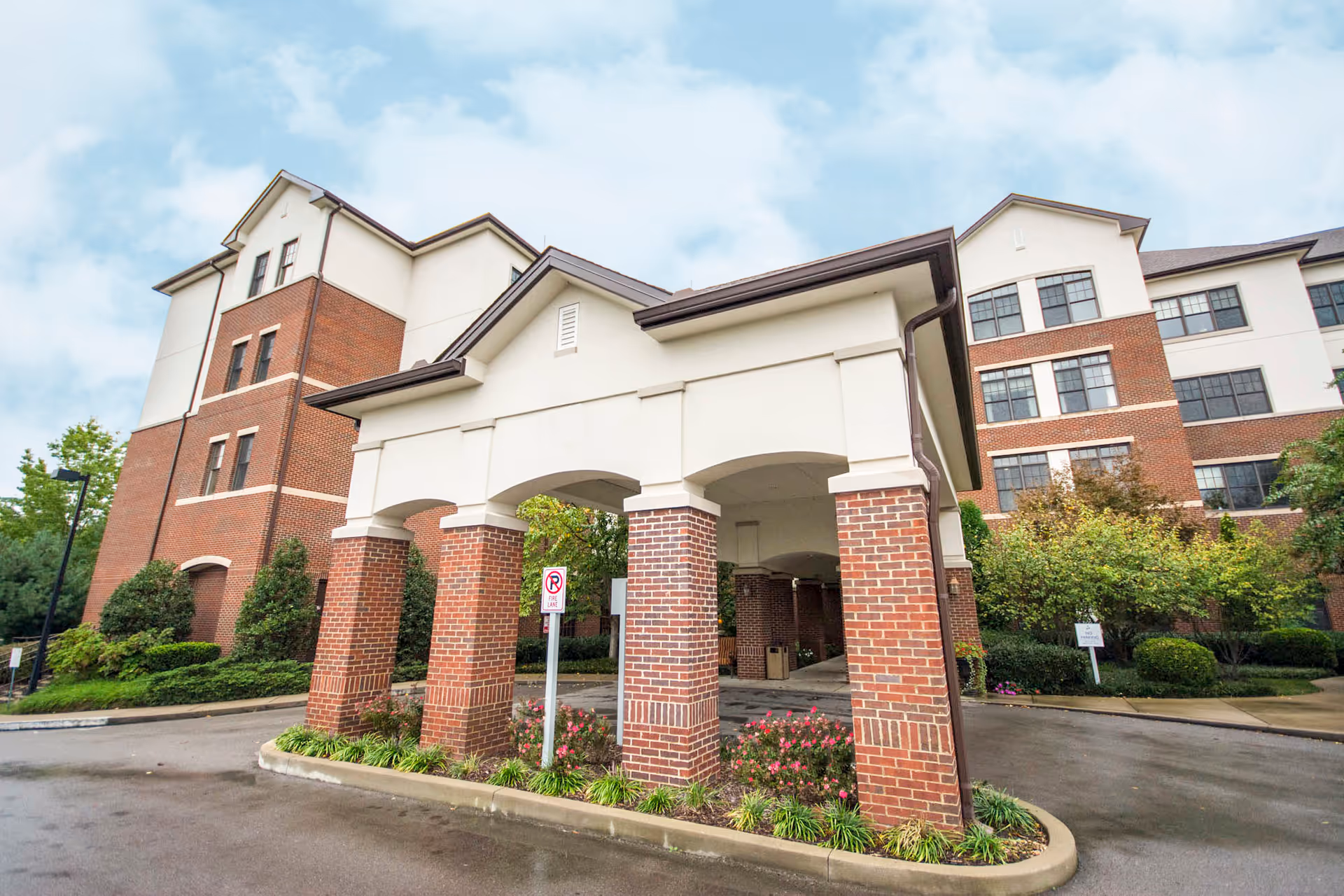 Exterior view of Brookdale Green Hills Cumberland with brick arches and landscaped entrance.