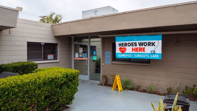 Entrance of Somerset Subacute Rehab showing double glass doors and a 'Heroes Work Here' banner.