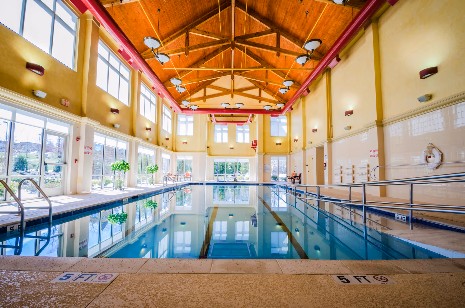 Bright indoor swimming pool inside Maryfield Nursing Home with high wooden beams.