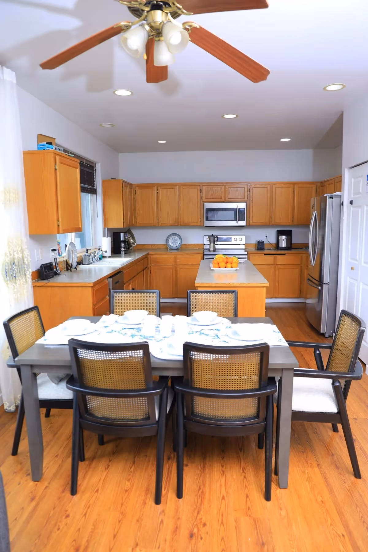 Bright kitchen with wooden cabinets, stainless appliances, and a dining table set for six.