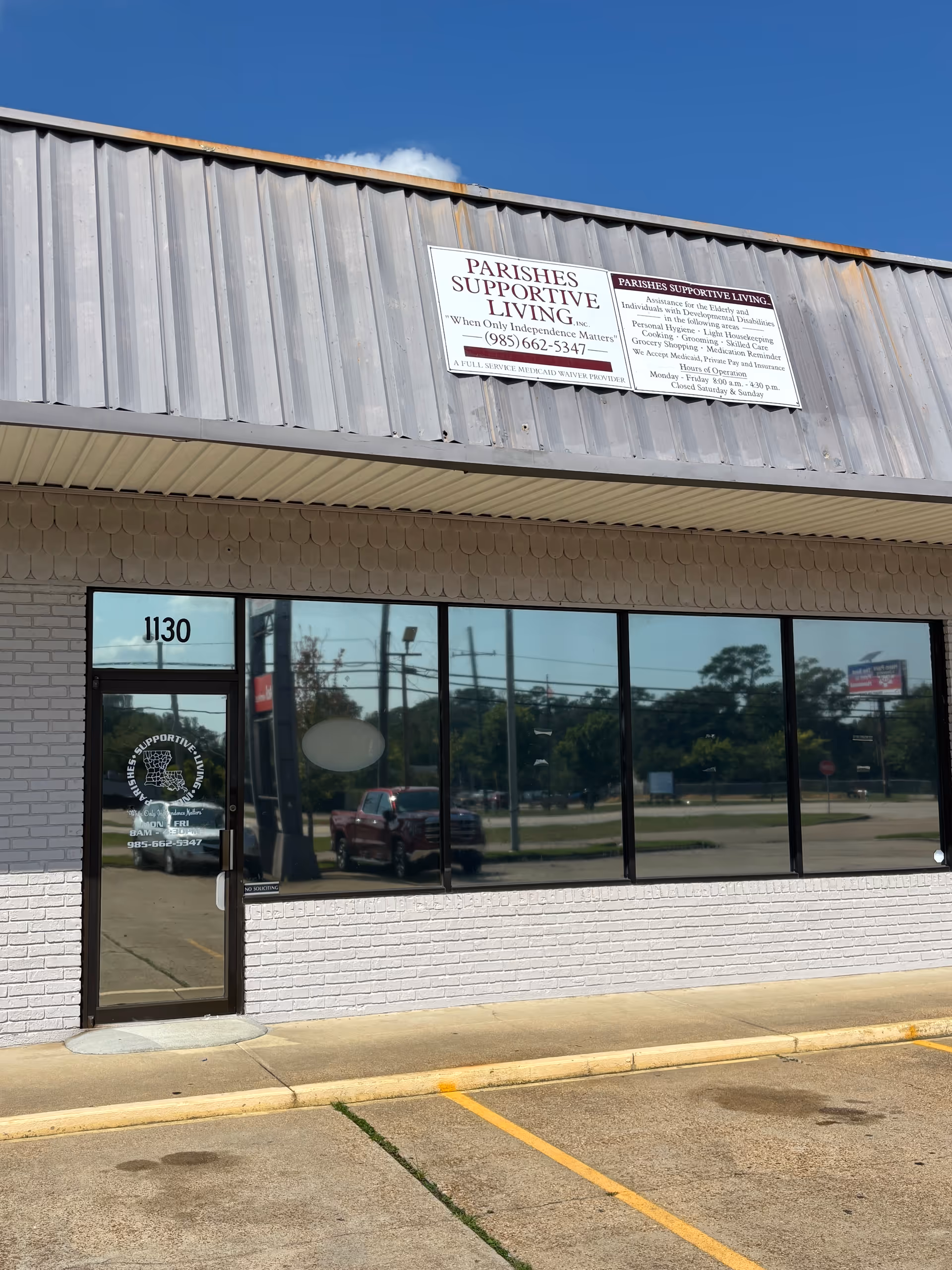 Front view of Parishes Supportive Living storefront with large glass windows and parking lot.