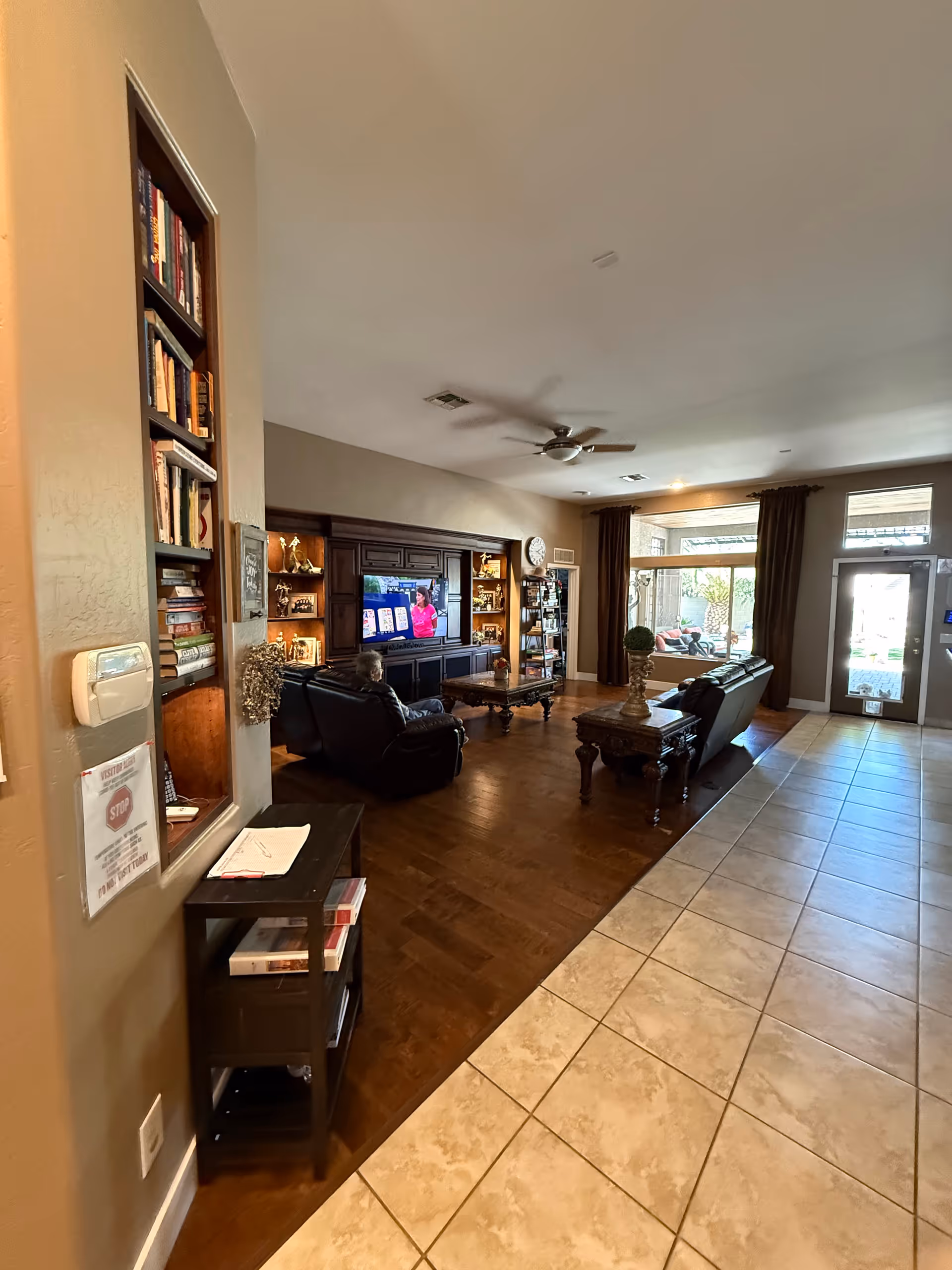 Cozy senior living lounge with TV, dark wood furniture, and comfortable seating.