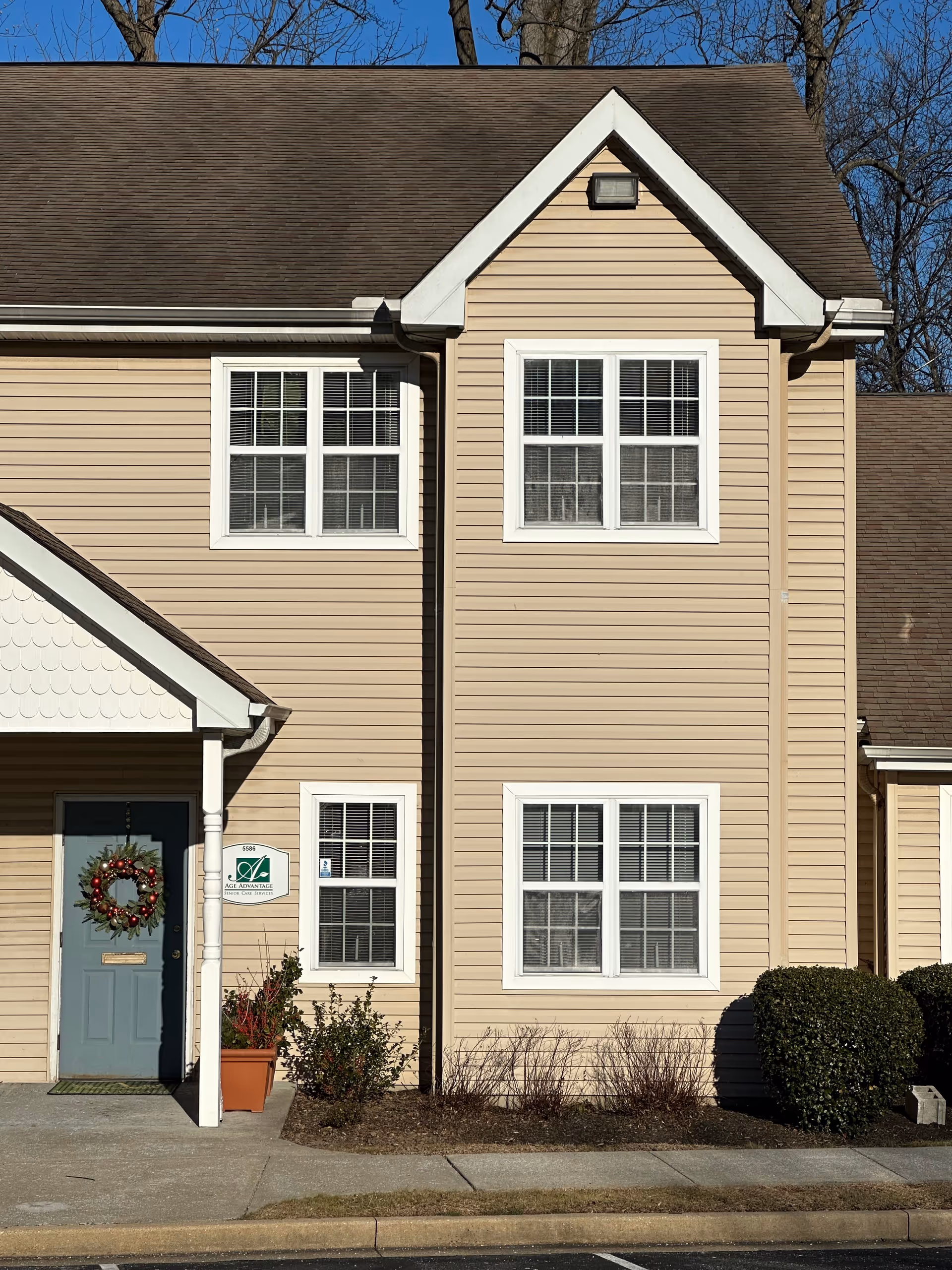 Beige two-story senior living building exterior with front door and wreath.