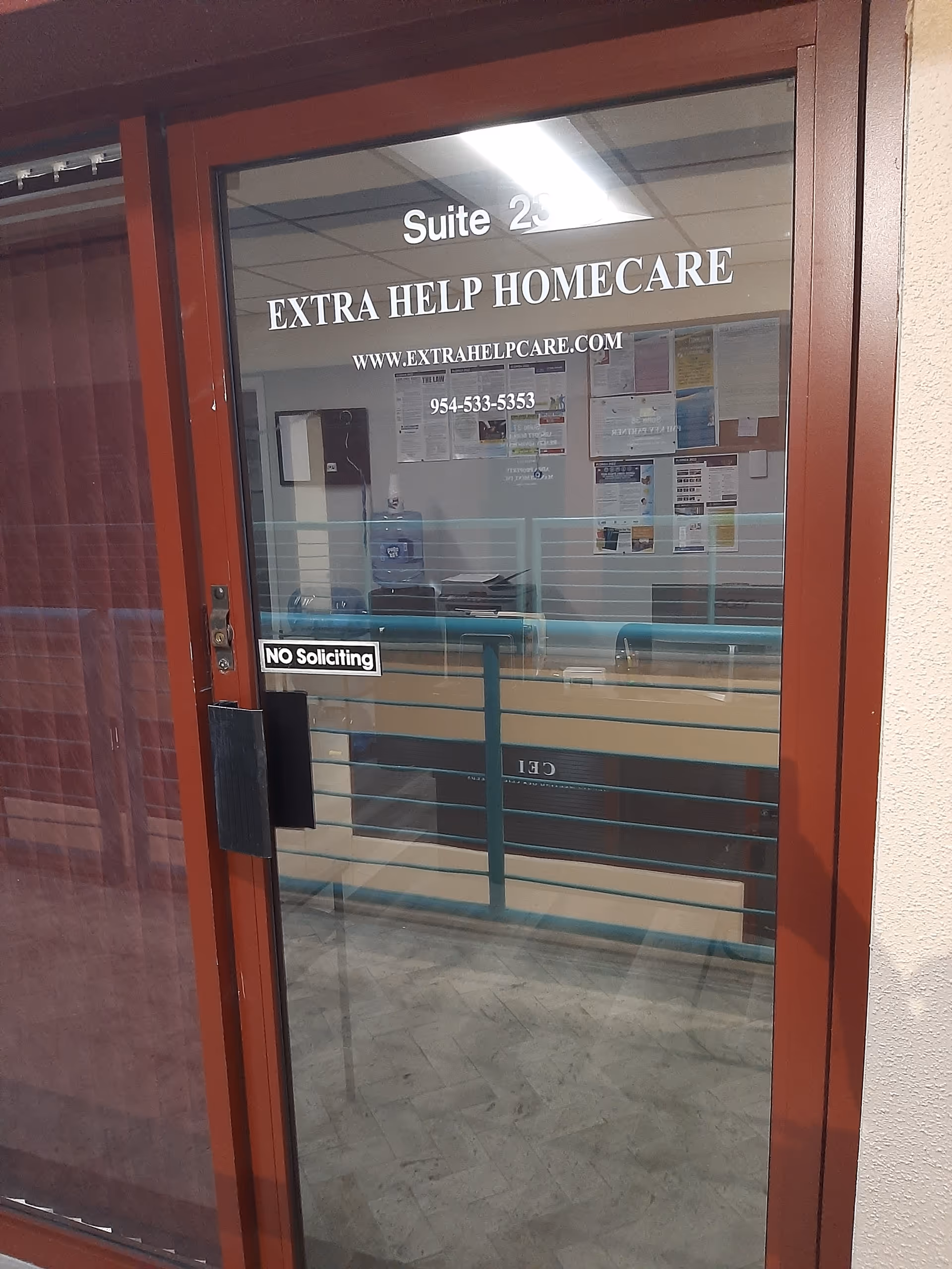Red framed glass door with Suite 25 and Extra Help Homecare signage, bulletin boards inside.