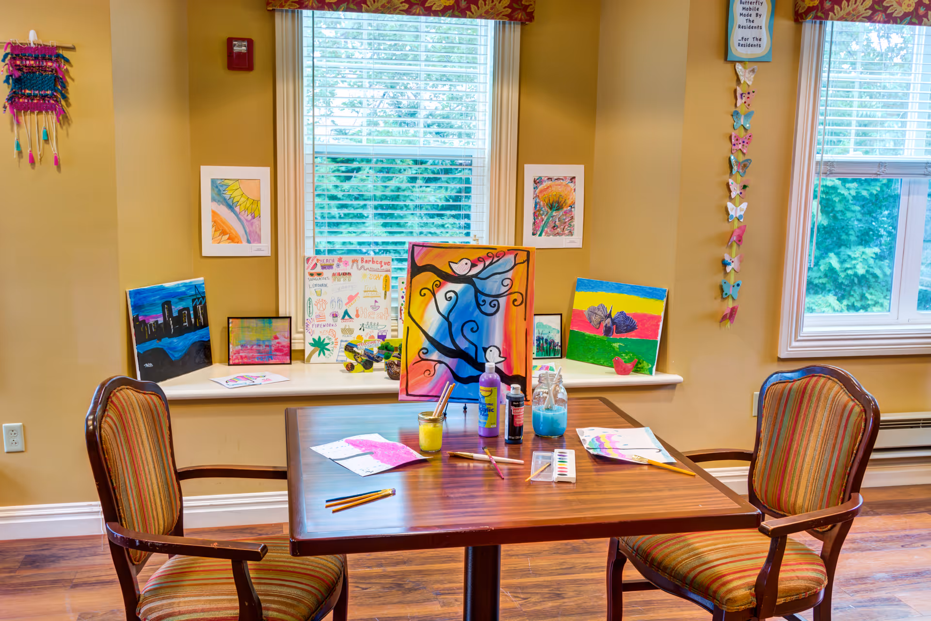 Art room in Symphony Manor senior living facility with a table and colorful paintings.