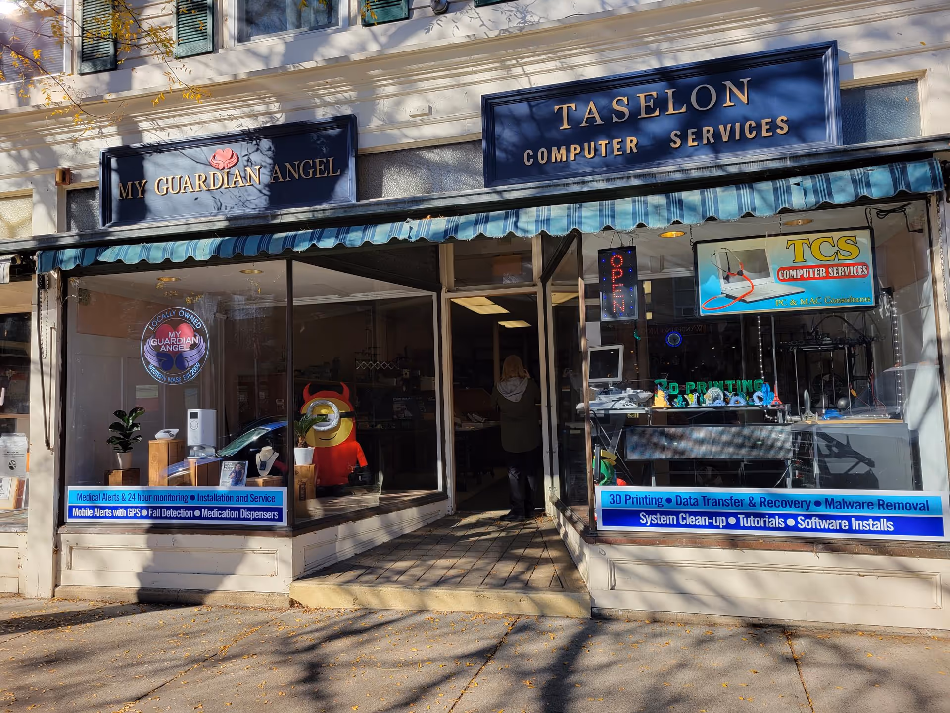 Two storefronts with blue signs, open sign, and a person entering the center shop.