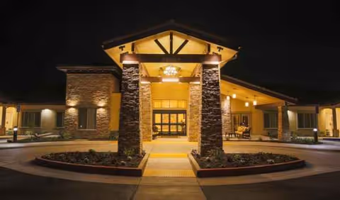 Night exterior view of Brightwater Senior Living of Highland entrance with stone pillars