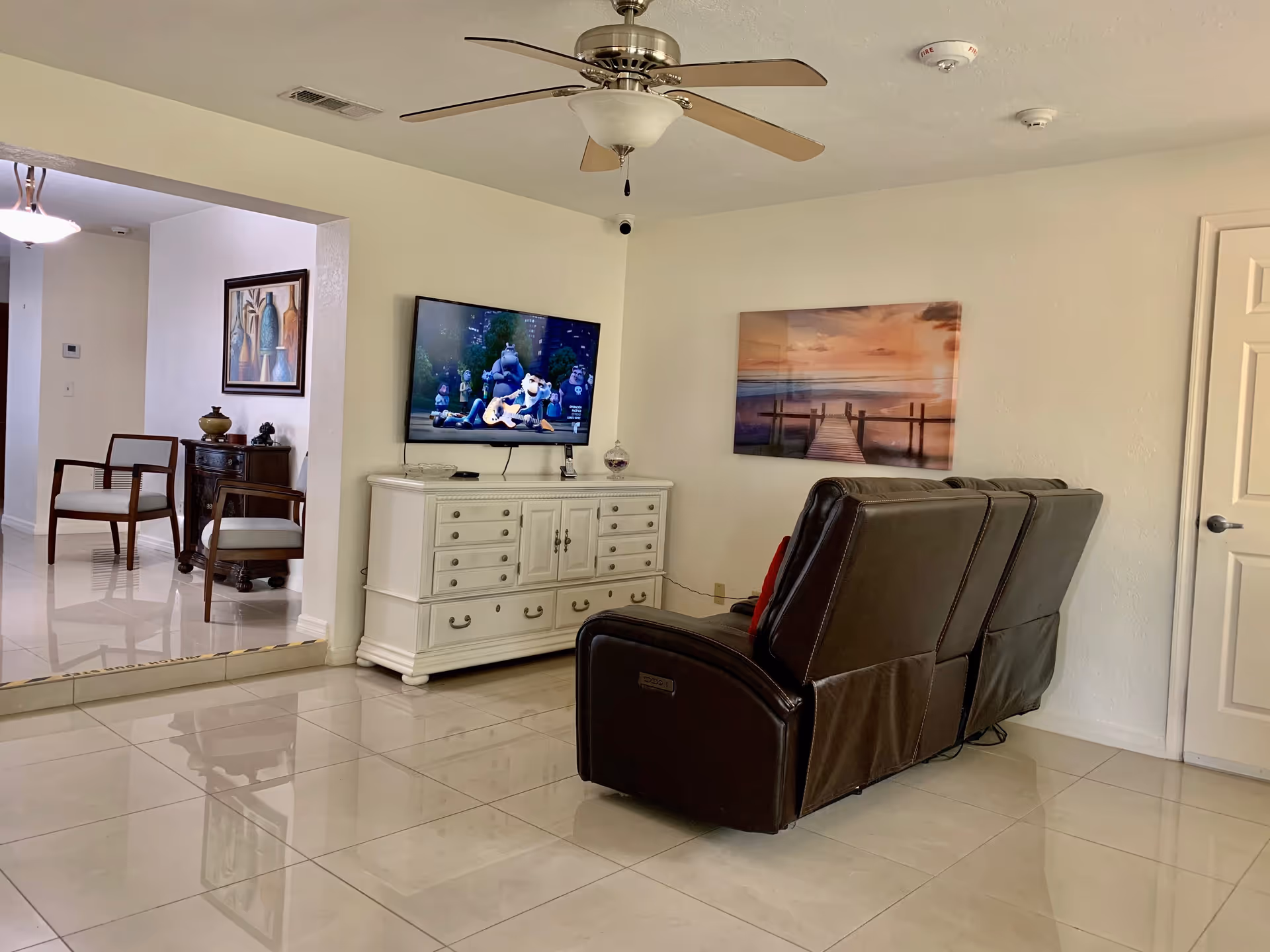 Living room area with leather recliner, TV on white cabinet, and wall art.