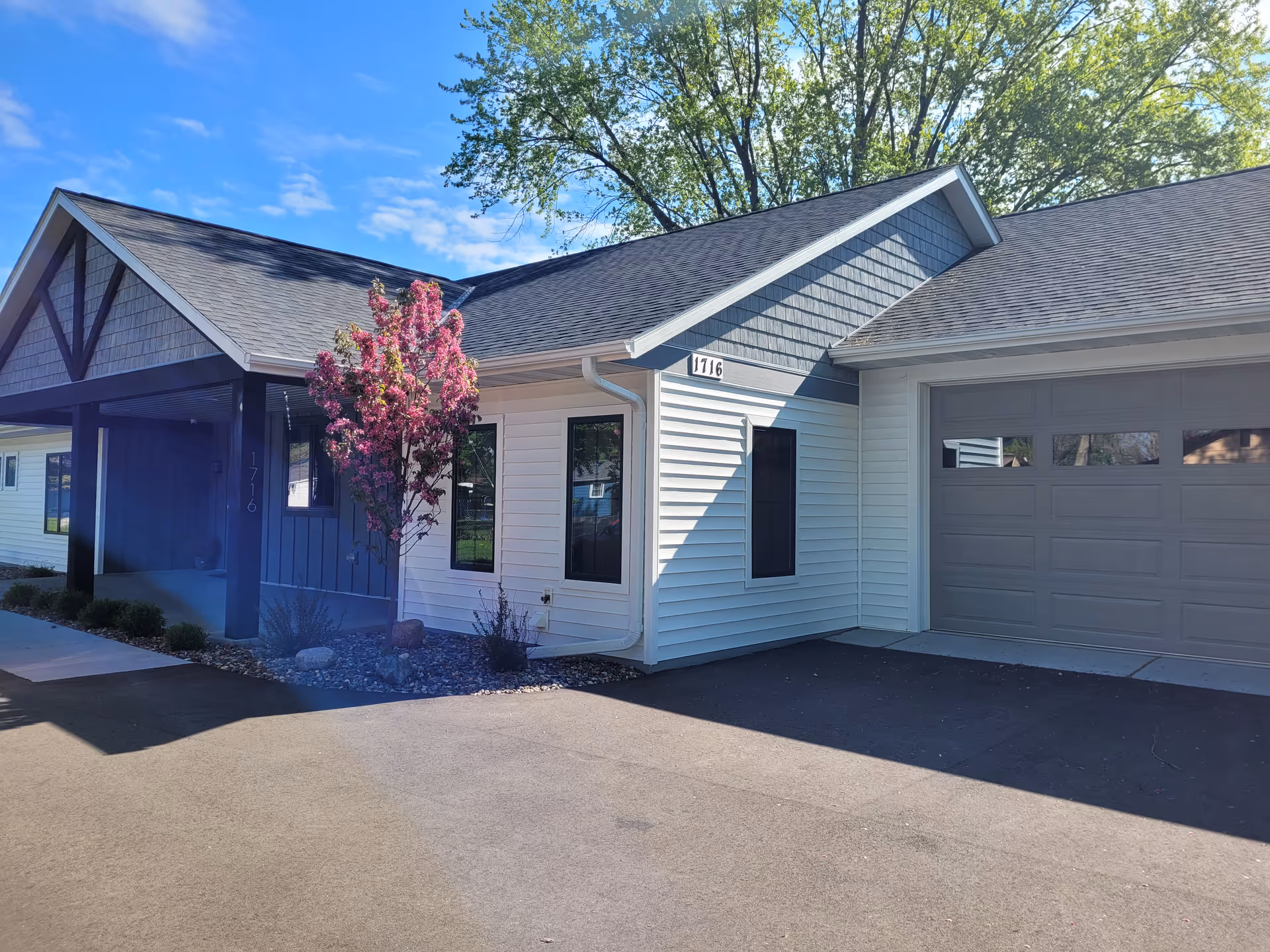 Modern senior living facility exterior with white siding, blue trim, and an attached garage.