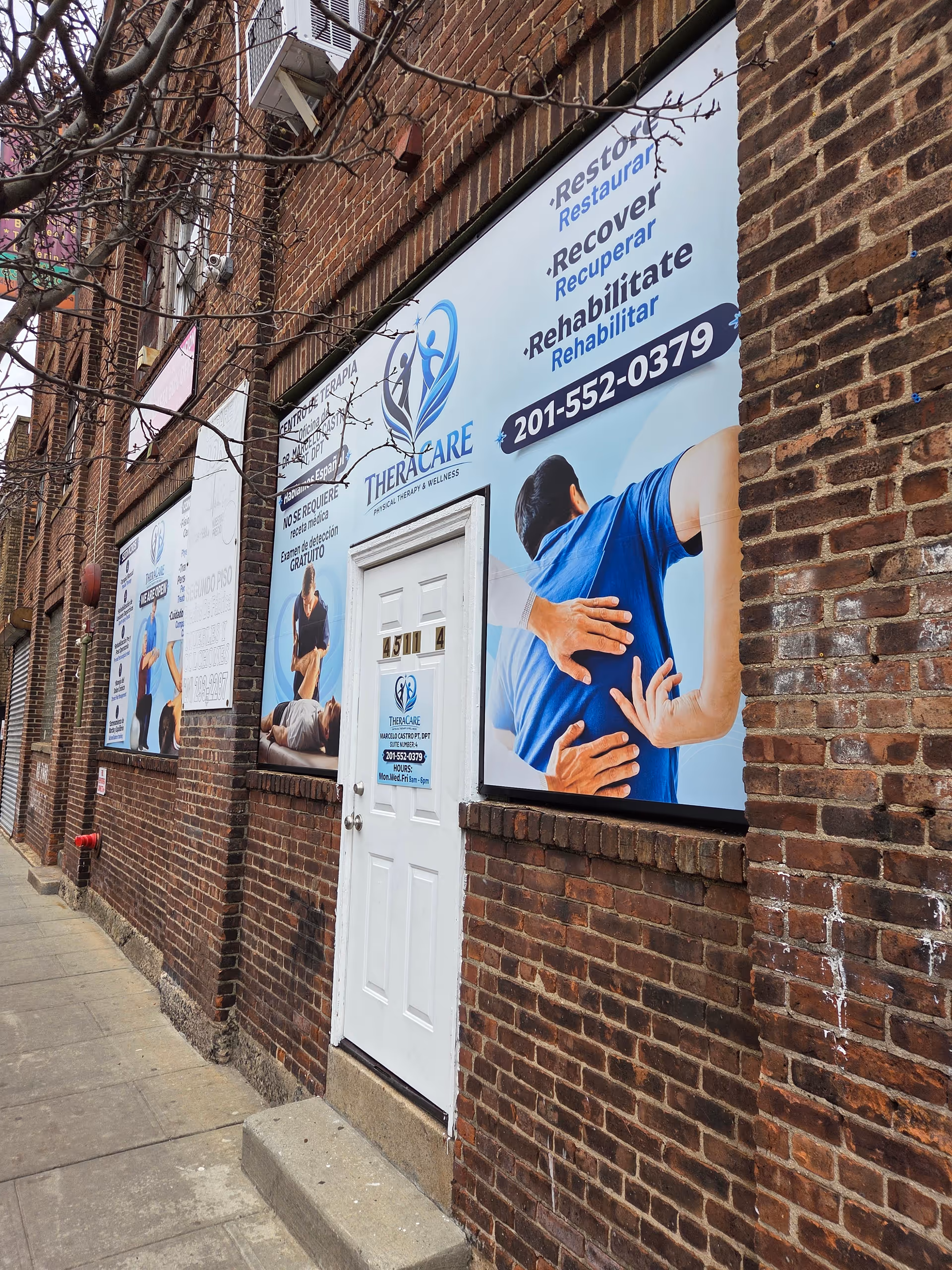 Brick building exterior with large TheraCare banners and a white door.