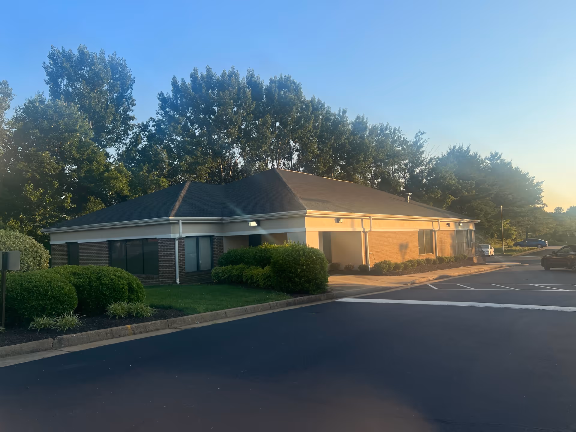 Single-story facility exterior with brick walls, manicured shrubs, and a parking lot.