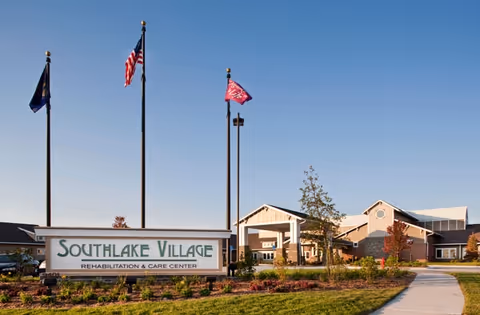 Exterior view of Southlake Village Rehabilitation and Care Center with entrance, flags, and landscaping.