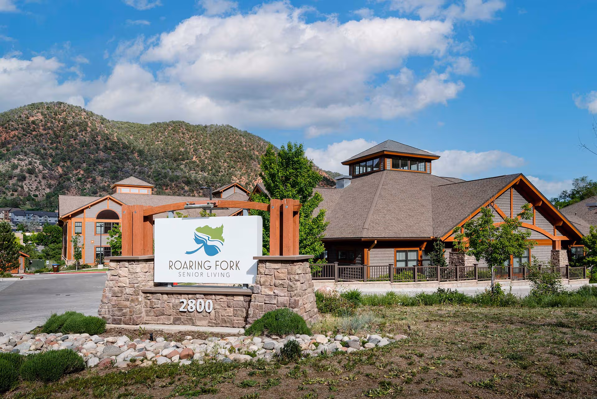 Front view of Roaring Fork Senior Living with sign and mountains in the background.