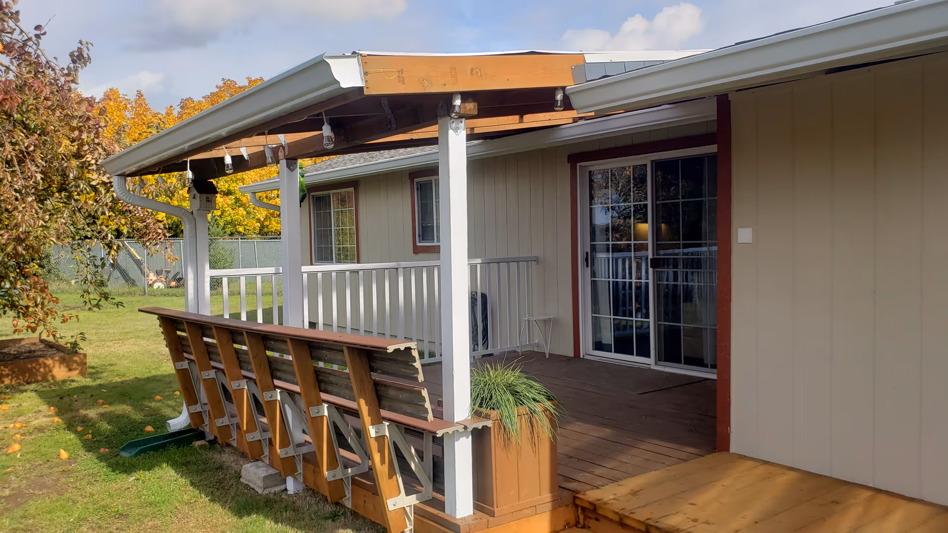Covered porch with wooden seating along railing and a sliding glass door.