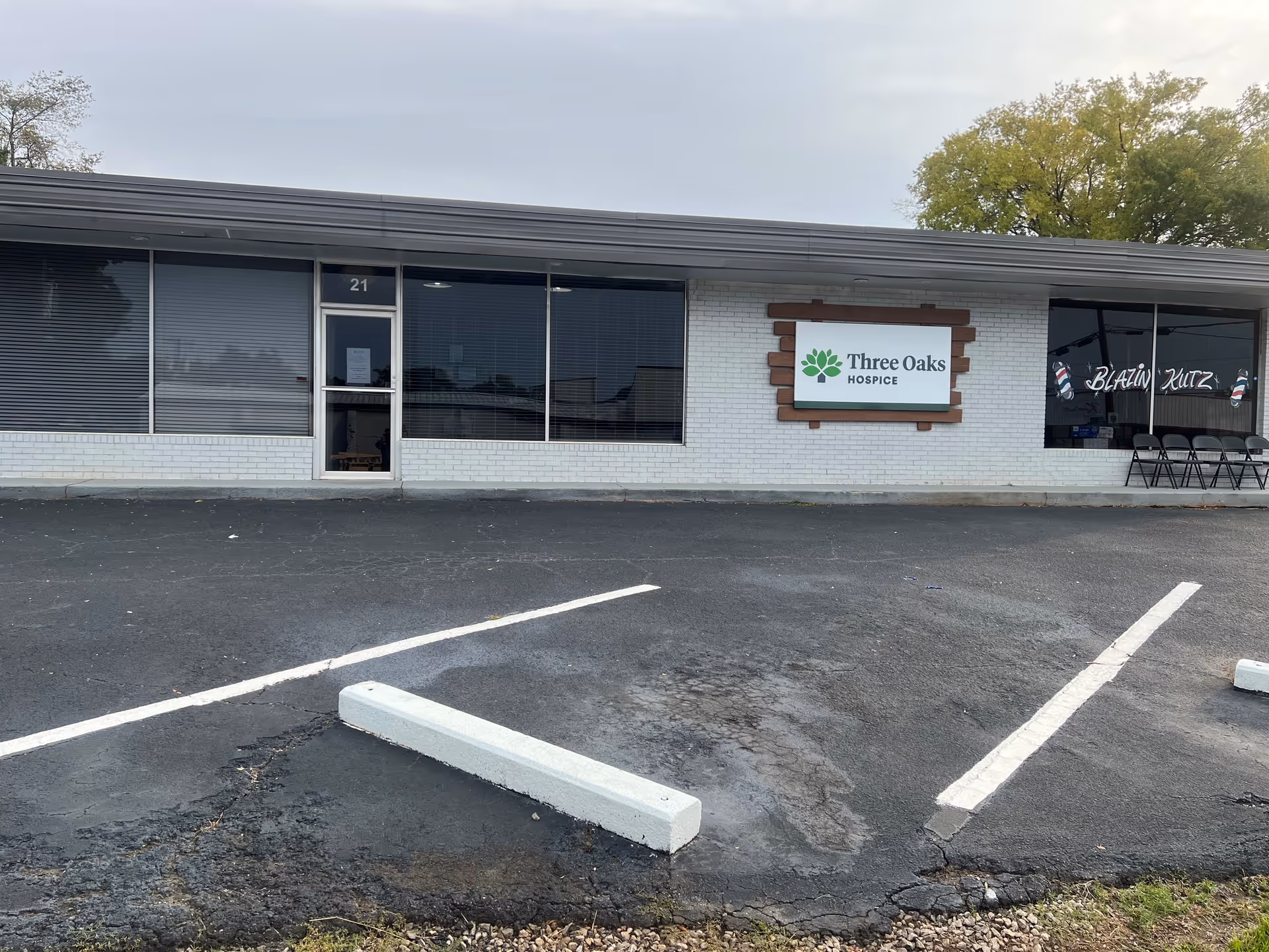 Exterior view of Three Oaks Hospice building with sign, large windows, and empty parking lot.