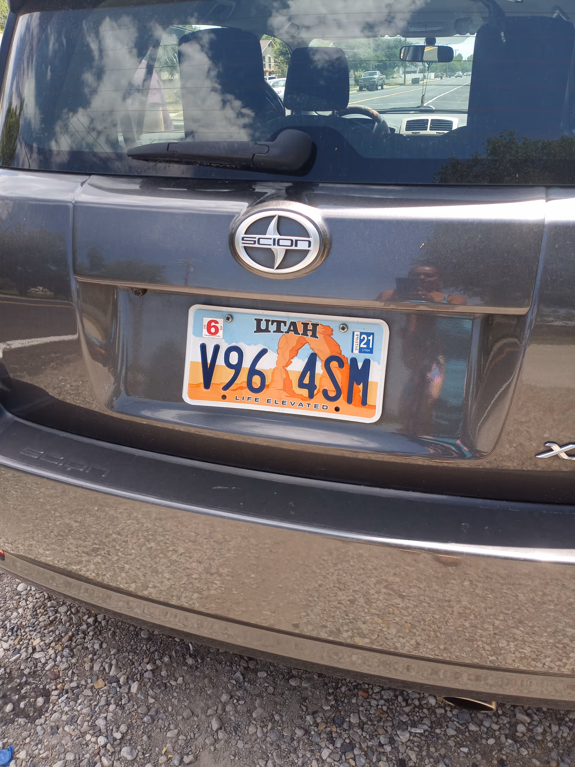 Rear view of a Scion vehicle with Utah license plate, parked on gravel.